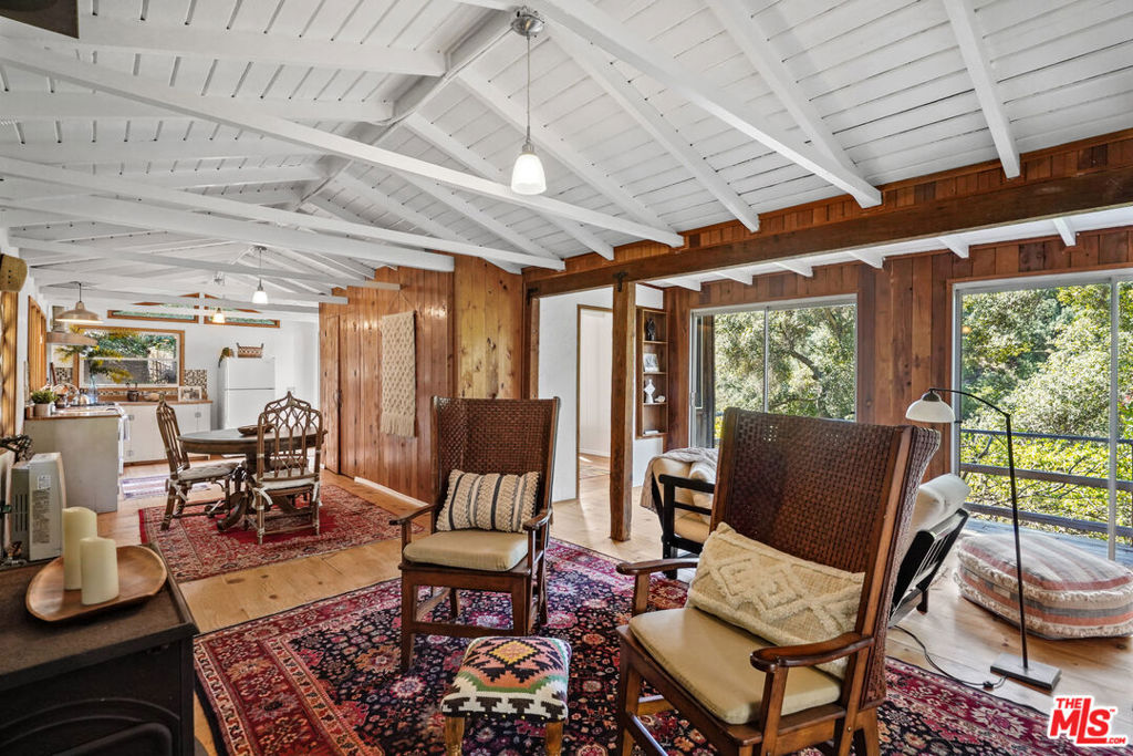 Enchanted Oak Crest! Mimi and Henry Smith's legendary artist home on nearly 2 lush acres has been given new life by the new owners, and now the charm filled main house is ready to welcome new dreamers to take up the life of this mountainside homestead, surrounded by epic views to the west of the "7 Sisters" mountain peaks, including Strawberry Peak, which are protected parkland. The property backs up to parkland, as well, ensuring privacy. Henry and Mimi bought the property in 1960 from the original Homesteaders. They became stewards of this living work of art, building up and out as their needs changed over the years. Artists, musicians, actors, and writers dwelt, and played, on the Oak graced land. Units have been continuously rented since the 1960s, often by famous artists and musicians, all inspired by the pristine land. Up a romantic stone staircase the 2 bed, 1 bath 1934 main house perches with panoramic views of the cluster of peaks across the canyon. Sunlight floods the pine floors, beamed ceilings, and old cedar walls. A woodstove cozies up the rooms. Doors flung open welcome the soft breezes. The kitchen and bath have been updated and new minisplits bring a new level of comfort. Decks take in the views and the sounds of the nearby creek. Stone walls grace old stone patios. Fruit trees give their bounty, herbs and flowers scent the air. Plant tomatoes, and veggies. Or visit Topanga's lovely farmers market. This epic home rests close to the village, the coast, the valley. Here on the mountain, the sounds of music, laughter and birdsong await your passion for the true Topanga Life.