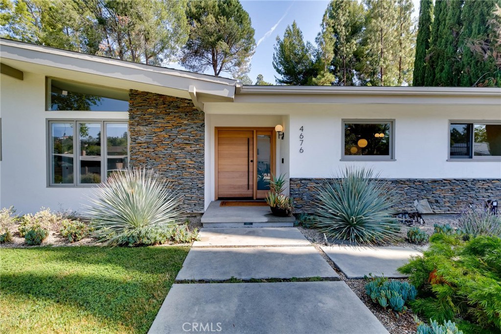 Motivated Seller! Mid-century modern stunner designed by a renowned architect, nestled on tree-lined street south of the boulevard in one of Tarzana’s most coveted neighborhoods. This beautifully updated single-story residence offers the perfect blend of luxury, comfort, and California indoor-outdoor living.
Set on nearly 15,000 sq ft of meticulously landscaped grounds, this 4-bedroom, 3.5-bathroom home spans 2,864 sq ft of light-filled living space. Clean modern lines and lush, drought-tolerant gardens frame the exterior, creating a peaceful, private retreat.
A custom wood front door opens into a bright, expansive living area with concrete floors, exposed wood-beam ceilings, and a striking double-sided fieldstone fireplace. Walls of glass line the back of the home, opening to a resort-style backyard complete with a heated pool, hot tub, outdoor fireplace, view terrace, and playset—ideal for year-round entertaining and family enjoyment.
At the heart of the home is the remodeled gourmet kitchen featuring an eat-in island, breakfast bar, custom white oak cabinetry, and stainless steel appliances—perfect for both casual meals and entertaining.
The luxurious primary suite is a true sanctuary, boasting spa-like bath with dual vanities and spacious walk-in closet. Three generously sized secondary bedrooms and updated bathrooms complete the interior layout.
Additional highlights include owned solar panels, drip irrigation, and eco-conscious landscaping for effortless, sustainable living.
A rare offering in an unbeatable Tarzana location—don’t miss your chance to call this architectural gem home!
