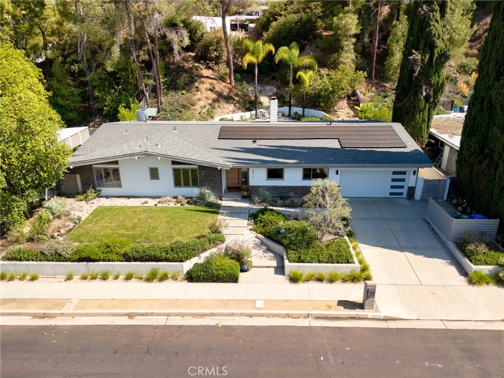 Mid-century modern stunner designed by a renowned architect, nestled on tree-lined street south of the boulevard in one of Tarzana’s most coveted neighborhoods. This beautifully updated single-story residence offers the perfect blend of luxury, comfort, and California indoor-outdoor living.
Set on nearly 15,000 sq ft of meticulously landscaped grounds, this 4-bedroom, 3.5-bathroom home spans 2,864 sq ft of light-filled living space. Clean modern lines and lush, drought-tolerant gardens frame the exterior, creating a peaceful, private retreat.
A custom wood front door opens into a bright, expansive living area with concrete floors, exposed wood-beam ceilings, and a striking double-sided fieldstone fireplace. Walls of glass line the back of the home, opening to a resort-style backyard complete with a heated pool, hot tub, outdoor fireplace, view terrace, and playset—ideal for year-round entertaining and family enjoyment.
At the heart of the home is the remodeled gourmet kitchen featuring an eat-in island, breakfast bar, custom white oak cabinetry, and stainless steel appliances—perfect for both casual meals and entertaining.
The luxurious primary suite is a true sanctuary, boasting spa-like bath with dual vanities and spacious walk-in closet. Three generously sized secondary bedrooms and updated bathrooms complete the interior layout.
Additional highlights include owned solar panels, drip irrigation, and eco-conscious landscaping for effortless, sustainable living.
A rare offering in an unbeatable Tarzana location—don’t miss your chance to call this architectural gem home!