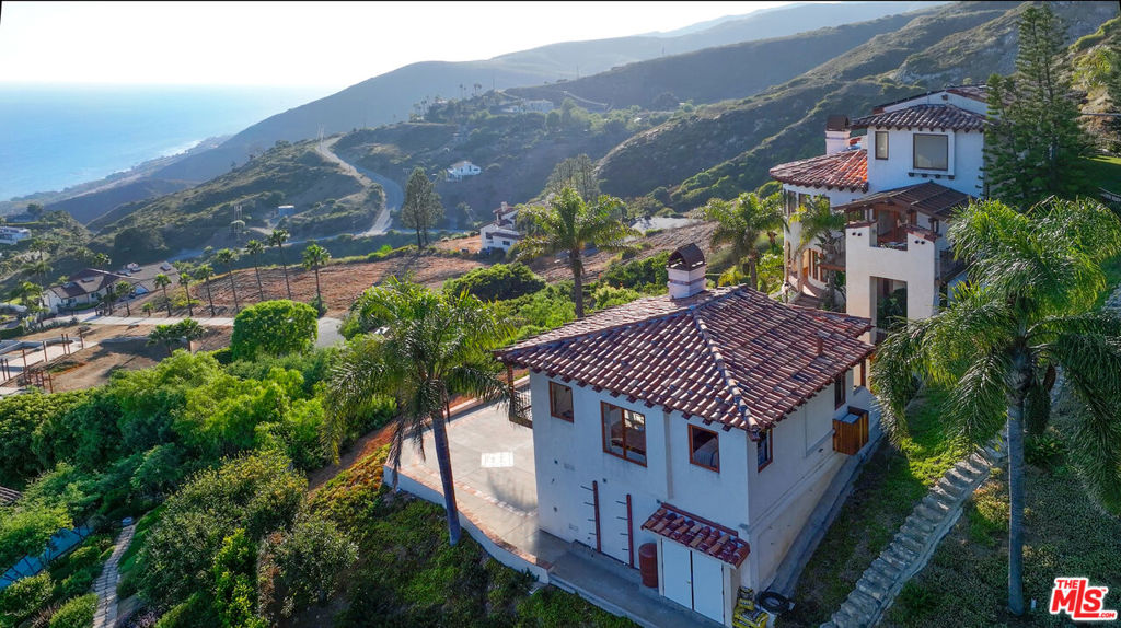 Perched above the Pacific on a quiet cul-de-sac in serene western Malibu, this sensational Mediterranean Villa captures some of the most expansive, unobstructed ocean and white water views in all of Malibu. Truly forever views that span the horizon from Catalina to the Channel Islands. Set behind gates and surrounded by natural beauty and magnificent rock formations, the home offers exceptional privacy and tranquility, while still being just a short scenic drive to the pocket beaches along the Encinal Bluffs, top-rated local schools, and gourmet shops like the Vintage Market. Thoughtfully designed with tremendous volume and architectural scale, the main residence welcomes you with soaring wood beamed ceilings, wide plank floors, and walls of glass that flood the interior with abundant natural light. There is an expansive living room with fireplace and endless ocean views. The family room and formal dining seamlessly connect to a gourmet chef's kitchen, complete with a curved island, custom lighting, and premium appliances perfect for entertaining or relaxed coastal living. A trellised, ocean-facing deck off the kitchen creates a seamless indoor-outdoor flow ideal for al fresco dining, BBQs, or simply enjoying the ocean breeze while watching the sun melt into the sea. The primary suite offers curved picture windows, a private ocean view deck, and a spa-like bath, while three additional bedrooms provide comfort for guests or family. In addition to a private office and studio guest apartment within the main structure, the property also offers a spacious, self-contained detached guest house with its own ocean view deck perfect for long-term guests, in-laws, or as a creative work space. Handcrafted details such as hand-painted tiles, tropical landscaping, and stone pathways add charm and character throughout. With an ample three car garage plus additional driveway parking and modern fire-safety infrastructure including a water storage tank, fire hydrants, and sprinklers this is a rare opportunity to securely enjoy the Malibu Lifestyle in the heart of nature.