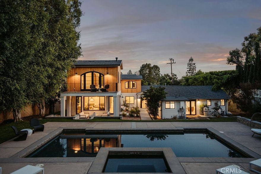 Discover a remarkable Villa Park estate designed for comfortable multi-generational living and effortless entertaining. Situated on over half an acre, this thoughtfully rebuilt 2024 residence offers refined design, luxurious features, and incredible versatility. The property includes a detached ADU (approx. 750 sqft) complete with a full kitchen, bedroom, bathroom, and laundry—perfect for guests, extended family, or a private office. Inside the main home, dual primary suites provide flexible living—one on the first floor with a serene garden-view patio, soaking tub, and oversized shower; the second upstairs, an expansive retreat (approx. 800 sqft) featuring vaulted wood ceilings, a stone fireplace, arched windows, and a custom $25,000 door that opens to a balcony overlooking your private yard. Warm Sahara Oak floors, solid wood arched doors, and soaring ceilings set the tone for quality craftsmanship throughout. The open-concept great room connects seamlessly to the outdoors via LaCantina Scissor doors, inviting year-round indoor-outdoor living. The chef’s kitchen impresses with top-tier appliances—Thermador Pro range, Bosch smart fridge, built-in microwave, and an oversized butler’s pantry for extra storage. Function meets style in the 200+ sqft laundry room, complete with dual washer/dryer hookups, a folding island, and a custom dog wash surrounded by clé tile. Step outside to your backyard oasis, where a Pebble Tec pool and spa are framed by lush landscaping, an additional 4,700 sqft of open space, and a thriving micro orchard with lemon, avocado, mango, guava, lime, and Kishu orange trees. Raised garden beds with automated irrigation make growing easy. With a spacious 6-car driveway and no HOA, this exceptional estate delivers rare comfort, space, and luxury. Come experience it in person—this one truly has it all.