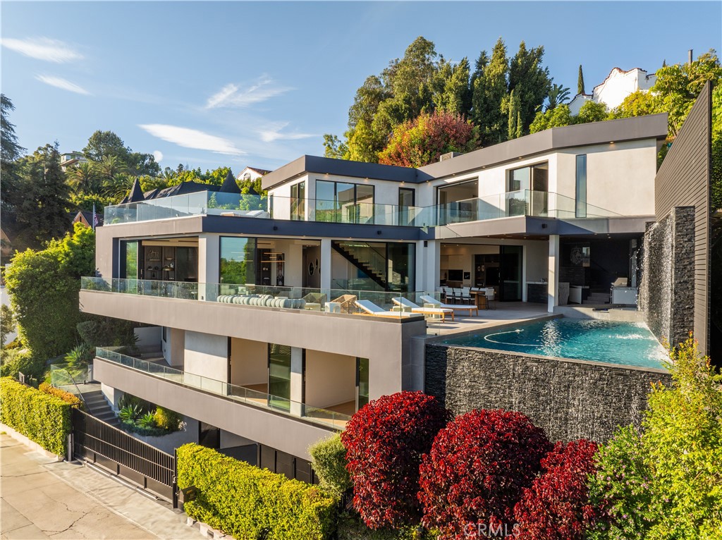 Welcome to this Modern Luxury Estate in the prime Hollywood Hills! With the best views of the city, this exceptional residence blends cutting-edge design with high-end finishes, offering the ultimate luxury living and entertainment. Spanning multiple levels, the home features 6 generously sized bedrooms and 7 bathrooms, each with en-suite configurations and custom walk-in closets. The entry-level boasts three guest suites, a state-of-the-art movie theater, and a full bar, creating a perfect setting for entertaining. The main living area showcases floor-to-ceiling sliding doors, seamlessly connecting indoor and outdoor spaces. The chef’s kitchen includes a large island, walk-in pantry, and premium appliances, opening to a resort-style deck complete with an infinity pool, rockwall waterfall, oversized hot tub, built-in BBQ, and wet bar, all overlooking stunning views of Hollywood. The top level is dedicated to the primary suite, featuring panoramic city views, a custom walk-in closet, and a luxurious bath with a soaking tub positioned to overlook Los Angeles. The primary suite has a private patio tucked away in the back with a private staircase to the pool. There's an additional en-suite bedroom, ideal for an office, also provides access to a private rooftop deck with unobstructed city views. On the lower level, you'll find another en-suite bedroom perfect for a gym or guest quarters. Additional highlights include a smart home system, full-service elevator, built-in surround sound, full security system, automated blinds, a 4 car garage, and a privately gated entrance. This one-of-a-kind estate offers a rare opportunity to own a truly unique and masterfully crafted property in one of Los Angeles’ most sought-after neighborhoods! Here's your chance to call it yours