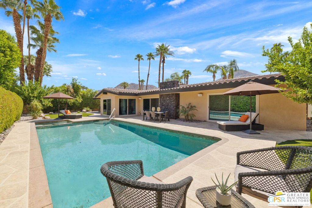 Mount Eisenhower sets a dramatic backdrop to this Indian Wells escape, walled, gated, and hedged for complete privacy and adjacent to the desert's most celebrated country clubs. Four bedrooms and four baths are framed by sparkling poolside living, two separate spas in distinct settings, and a series of outdoor gathering spaces designed for both quiet relaxation and lively entertaining. Outdoor living beautifully frames the home front and back. The rear yard offers a private pool and spa wrapped in tall hedges, while the front patio features a waterfall spa + fire pit with mountain views. An outdoor kitchen with bar seating beneath a gazebo includes a built-in barbecue, separate burner, refrigerator, and TV. French doors and sliders open the home seamlessly to these spaces from every angle. Inside, the open-concept living areas feature large travertine tile floors, tall ceilings, and abundant natural light. The living room centers on a stone fireplace and is currently enjoyed as a billiard lounge, opening to the south patio with views, fountain, and waterfall spa. The family room offers another fireplace and connects effortlessly to the redesigned chef's kitchen with vaulted beamed ceilings, island, counter seating on two sides, double ovens, two dishwashers, wet bar with wine cooler, and a breakfast room with 180-degree views of the private backyard. Bedroom design is exceptional, with three primary-sized ensuites offering separation and scale. The west-wing primary suite opens to the pool and features a walk-in closet with built-ins, separate tub, and shower. Another suite at the opposite end opens to the yard and includes dual vanities, a glass block shower, and a garden patio off the bath. A third ensuite opens to the front patio with its own walk-in closet. The fourth bedroom enjoys backyard views with an adjacent full bath and nearby utility room with sink. Additional highlights include a 2-car garage with extensive built-ins, guest parking behind gates, rooftop solar, and lush landscaping throughout. Take the Matterport Virtual Tour for a better sense of the flow. The best of Indian Wells living is here, with El Paseo's shopping and dining just a short drive away.