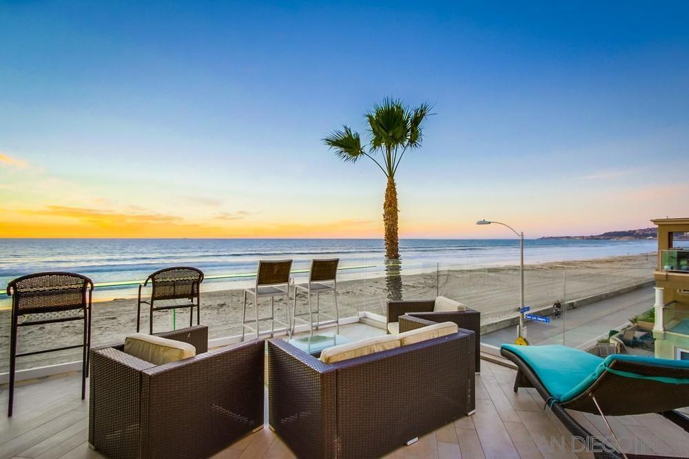 Soaring above the sand in a sleek 4-residence building, this top full floor penthouse delivers the Mission Beach dream with uninterrupted ocean panoramas from nearly every room of floor to ceiling glass and sliding glass doors. A studs-out, designer remodel introduced a folding NanaWall that dissolves the entire west façade, erasing the line between a light-flooded great room and an extraordinary wrap-around deck with glass rail that stretches the building’s north side. Entertain against a backdrop of surf and sunsets beside the indoor/outdoor pass-through fireplace, then step onto porcelain flooring that flows seamlessly outside. The open kitchen anchors the space with waterfall quartz, premium stainless appliances and bar seating that frames the blue horizon, while a circular dining nook offers fireside meals for six. Three refined bedrooms accommodate up to ten guests: a view-filled primary retreat with spa tub, rain shower and fireplace; a guest suite with dual queens; and a clever Murphy-bed suite/office. Floor-to-ceiling glass, smart TVs in every room, stacked laundry, central A/C, and curated furnishings ensure turnkey ease. Exclusive deck space includes a stainless BBQ, lounge chaises and dining for eleven; the tandem garage (approx. 30' deep) plus street and public lots solve parking. With only three other homes in the building and the boardwalk at your doorstep, this residence is equal parts trophy, sanctum and high-yield vacation asset. ****