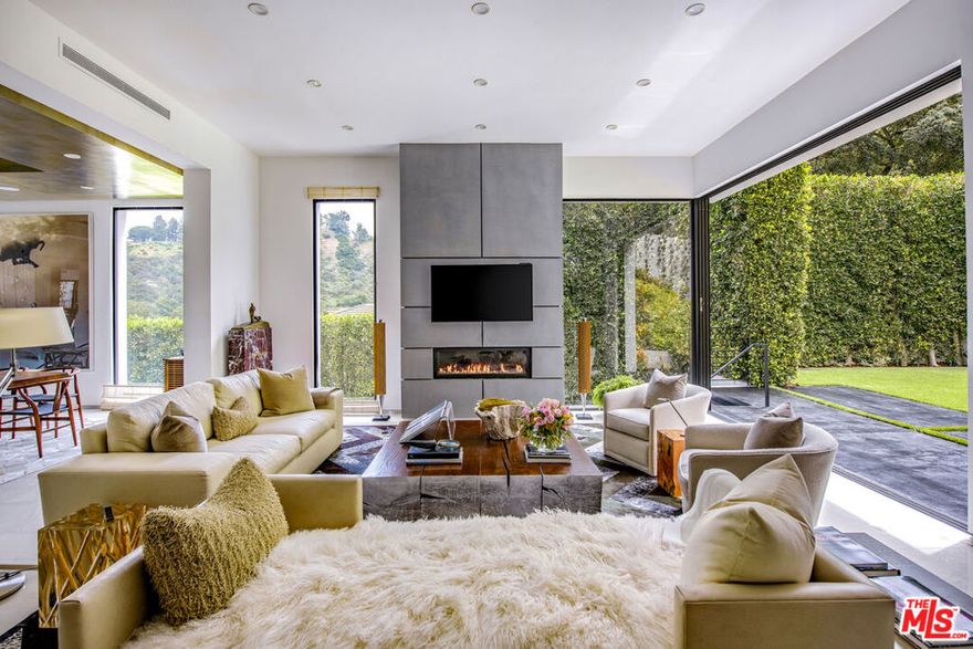 Exceptional modern estate, quietly nestled at the end of a peaceful cul-de-sac, offering a rare sense of serenity and seclusion in the heart of one of the world's most iconic neighborhoods. Surrounded by lush natural beauty and designed for secure, elevated living, this private retreat spans approximately 9,000 square feet of meticulously curated space that blends contemporary sophistication with the calm of a high-end resort. This estate goes beyond the ordinary with its fully customized indoor golf simulator featuring the same Full Swing Golf system used by Tiger Woods. Instead of a traditional home theater, this one-of-a-kind space offers a luxury sports experience at home, complete with immersive visuals, pro-level performance tracking, and realistic course play from world-famous greens. Smart home features include Sonos audio, iAquaLink pool control, Lutron lighting, and Nest climate systems, all designed to elevate modern living. The gourmet kitchen is appointed with top-tier appliances and sleek finishes ideal for both entertaining and everyday enjoyment. The primary suite serves as a tranquil sanctuary with dual marble-clad baths and generous his-and-hers walk-in closets. Six additional bedrooms offer flexible living, easily transformed into guest suites, executive offices, a gym, or a man cave. Recent upgrades to the estate enhance both function and aesthetics. Outdoors, the property transforms into a private oasis. A dramatic infinity-edge pool invites relaxation, while a spa, lush lawns, multiple water features, and a breathtaking living wall of succulents create a truly immersive, resort-like environment. With parking for six vehicles and every detail carefully curated, this estate offers elevated living in every sense. Nestled in one of Beverly Hills' most coveted enclaves, this extraordinary residence offers an unparalleled sanctuary of refined elegance, tranquil privacy, and unmistakable prestige more than a living space, it is a bold statement of ultimate luxury and distinction.