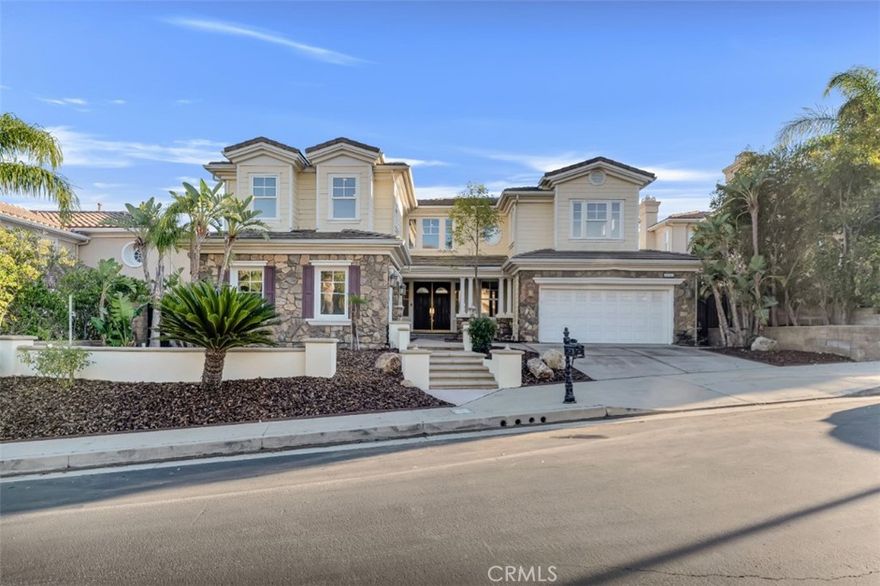 Embrace luxury living in this magnificent 5-bed, 5-bath, nearly 5,000 sqft residence, located in prestigious guard-gated Renaissance community of Porter Ranch. Set on prime elevated lot with breathtaking mountain & valley views, this grand estate combines timeless elegance with contemporary sophistication. The exterior showcases drought-conscious landscaping, stately natural stone accents, wood siding & beautifully colonnaded covered porch. Inside, a formal entryway welcomes you home with fresh interior paint, new carpeting & thoughtful touches throughout, like recessed lighting, high ceilings, dual zone AC & so much more! The formal living room makes a statement with soaring two-story ceilings, marble-surround fireplace, & custom built-ins. The formal dining room exudes refinement with a decorative tray ceiling, rounded bay windows. The gourmet kitchen is a chef’s dream featuring dark wood cabinetry, granite countertops, a central island with auxiliary sink, stainless steel appliances including built-in double ovens, a sunny breakfast nook with a curved bay window, & breakfast bar seating. The adjoining, open family room offers relaxed sophistication with a cozy fireplace & views of the mountains. A private bedroom with en-suite ¾ bath makes a perfect, private, guest suite while a den/office space, provides a quiet workspace & could be easily converted into an additional bedroom. Additional features include a convenient powder bath, dedicated laundry room with utility sink & storage space, & 2 attached garages, with direct access, offering parking for 3 cars. Upstairs, the luxurious primary suite is a private sanctuary with double-door entry, tray ceiling, sitting alcove, French doors to a private balcony with panoramic views, & a spa-inspired bath boasting dual vanities, soaking tub, walk-in shower with dual shower heads, & a massive walk-in closet. 2 additional bedrooms each feature en-suite baths & generous closets, while the upstairs bonus room offers flexibility as a media room, home gym, or study. The backyard is a true retreat, complete with a sparkling pool & spa, pergola-covered patio, & a built-in BBQ/outdoor kitchen designed enjoy the sweeping views. This home embodies comfort, style, & sophistication, with access to community amenities, including tennis courts & manicured grounds, all within minutes of The Vineyards shopping center, fine dining, & top-rated schools. Don’t let this one pass you by!
