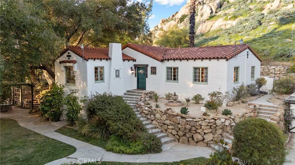 Standing proudly on an elevated perch, in this private almost “SECRET” neighborhood sits The Starke House, a 1929 Spanish Revival home nestled at the base of Mt Rubidoux. This historic gem has gone through an extensive restoration. On the ground floor, sits a delightful studio apartment. This is a one-bedroom ensuite with convenient kitchenette and bathroom, featuring a brand new mini-split system, and refinished Douglas fir floors. Granite stone retaining walls and cobblestone steps lead you up to the main entrance. The expansive living room boasts incredible plaster tray ceilings, custom floral wrought iron sconces, wood-burning fireplace and quarter-sawn oak floors. A French door opens onto a deck, where mature live oak trees cast a dappled shade and soak in the captivating views. Elegance abounds in the formal dining room, illuminated by a stunning restoration hardware solid brass chandelier. French doors lead out to a charming patio, complete with a fire pit, perfect for al fresco gatherings under the starlit sky. The charming kitchen equipped with updated appliances flows seamlessly into the dining room. Off the kitchen is a convenient laundry room. No expense spared renovating the main bathroom. Double arches, venetian plaster walls, and a custom Spanish Revival vanity, topped with Carrera marble add a touch of luxury. A large soaking tub beckons for relaxation, while the spacious walk-in shower features unlacquered brass fixtures from Morocco.. The half bath off the hall echoes the same luxuriousness, with venetian plaster, Restoration Hardware vanity topped with Carrera marble, and one-of-a-kind antique, art-nouveau mirror. Two generously sized bedrooms offer tranquil escapes, each adorned with custom sconces and framed by picturesque views through the restored casement windows. One of the many benefits of this private location is its proximity to so many outdoor activities. Take a private trail from your doorstep that winds its way up Mount Rubidoux, the most scenic hiking spot in the I.E. At the bottom of the street is the Santa Anna bike path, 110 miles of scenic trails from the San Bernardino County National Forest to the Pacific Ocean in Huntington Beach. Have the peace of living in a serene setting among nature, yet the convenience of being a part of the vibrant Downtown culture, with many restaurants, bars and museums.
