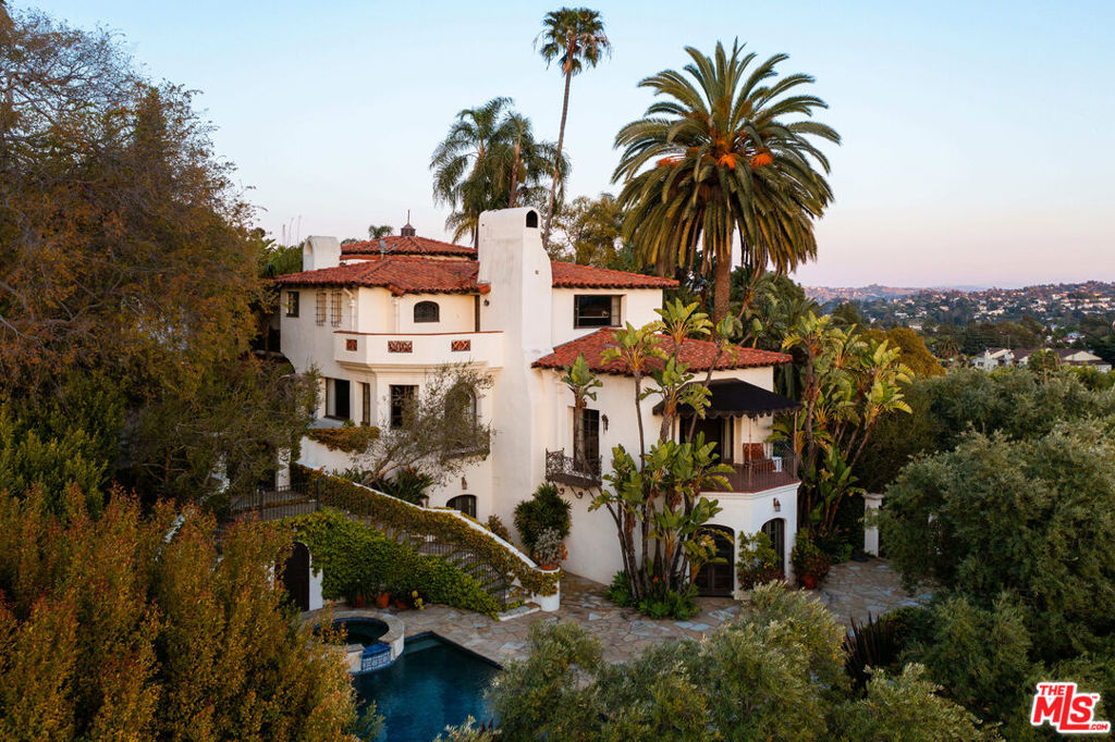 This rare opportunity to own one of Los Angeles' most prestigious estates, the Oliver R. Fuller estates, was conceived in 1929 by celebrated architect Harry Hayden Whiteley, AIA. A stunning Spanish Colonial Revival masterpiece stands behind stately wrought-iron gates, offering unparalleled privacy and distinction. As you approach the graceful private drive, you are welcomed by the majestic allure of a Mediterranean estate steeped in old Hollywood glamour. Nestled on over 39,000 square feet of lush, manicured grounds, this magnificent property boasts six bedrooms, 11 bathrooms, and commanding views across the LA basin, crowned by the iconic Griffith Observatory. Upon entry, you are greeted by a grand two-story rotunda, where hand-painted ceilings and a sweeping staircase evoke the elegance of a bygone era. The opulent living room, adorned with an intricate fireplace, opens through French doors to a balcony overlooking the shimmering pool, spa, and the sparkling cityscape beyond. Bathed in natural light, the library enchants with its honeycomb coffered ceiling, stained glass windows, a warm fireplace, and a hidden Prohibition-era bar.The formal dining room, a work of art, features a hand-stenciled wood ceiling, breathtaking city views, and glass doors leading to a covered veranda. Here, you can bask in the warmth of an outdoor fireplace while gazing over the enchanting city below. The expansive chef's kitchen with a Butler's pantry, commercial-grade appliances, and an oversized Mahogany-clad island effortlessly combines modern convenience with timeless sophistication.A graceful wrought-iron circular staircase leads to five lavish bedroom suites; each meticulously restored to offer modern luxuries while preserving its classic charm. The primary suite is a tranquil sanctuary featuring a fireplace, stained glass details, and a spa-like bathroom with awe-inspiring city views. On the lower level, discover an entertainer's paradise with a spacious media room, home gym, 2,500+ bottle wine cellar, and two additional bathrooms, including one with a steam sauna. Perched above the estate, a charming one-bedroom, two-bathroom guest house awaits. It offers a private living room, kitchenette, and porch with sweeping rooftop and city views. This secluded retreat is ideal as a guest residence, studio, or home office. More than a residence, it celebrates historic elegance and modern luxury, set against one of the most breathtaking vistas in Los Angeles.