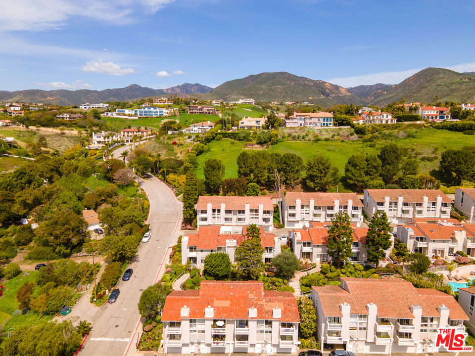 Enjoy ocean views and a prime location in Malibu Villas. This bright, end-unit townhome offers a spacious layout with classic charm. The main level features a formal entry, coat closet, and a comfortable living room with a wood-burning fireplace, wet bar, and sliding doors that open to a sunlit terrace. A powder room and dining area connect to an open-air atrium, ideal for indoor-outdoor living. The kitchen includes a cozy breakfast nook and direct access to the patio. Upstairs, two en-suite bedrooms offer generous space and storage, including a primary suite with ocean views, a private balcony, and a dual-sink vanity. The attached two-car garage provides direct entry to the kitchen and includes laundry. Community amenities include a pool, spa, sauna, and clubhouse. Ideally situated across from Paradise Cove with easy access to Pepperdine University, Point Dume, Zuma Beach, Malibu Country Mart and Trancas Country Market. Property can be leased partially furnished -or- unfurnished, at the same price.