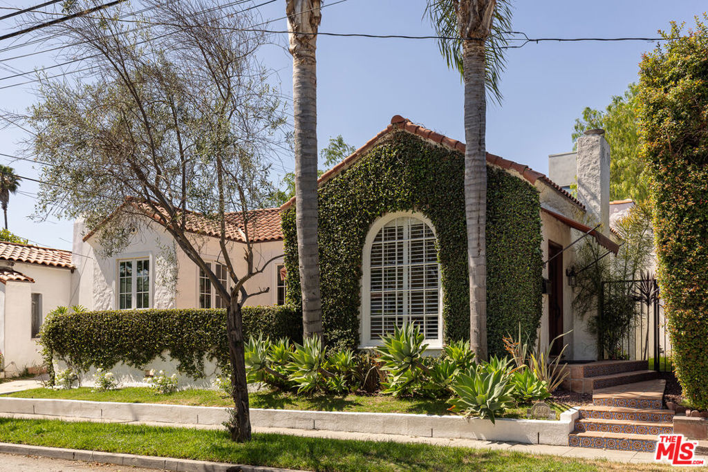 Come fall in love with this exceptional Spanish home at 8009 Clinton Street. The 2BR/2BA stunner (c. 1925) boasts a fabulous floor plan and a convenient, sought-after location right in between the coveted West Hollywood and Melrose neighborhoods. This spectacular character-rich gem is bathed in natural light, and the ease of living will welcome you home each day. Nestled graciously just above the street for privacy, the home is introduced by an enchanting Saltillo tile walkway leading you to an impressive front door moment. Once inside, you'll be greeted by an expansive, show-stopping living room featuring soaring barreled ceilings, decorative fireplace and mantel, built-in shelving, hardwood floors throughout, and an incredible arched picture window complete with plantation shutters. The living room offers direct access to the inviting enclosed front patio oasis, where you can re-energize every morning with a cup of coffee and wind down in the evenings with a glass of wine and good conversation. Stairs from the spacious living room flow seamlessly into the oversized formal dining room through character archways, offering you views to the lovely front yard. The galley-style kitchen comes complete with stainless steel appliances, recessed lighting and an adorable attached eat-in breakfast area featuring original built-in cabinetry and surrounded by windows and natural light. Two gracious bedrooms can be found along the rear of the home - one boasts an ensuite bathroom with standing shower and sizable walk-in closet, while the other includes a built-in desk that would make for a terrific office/work-from-home space. Between the two bedrooms, there is an additional oversized full bathroom (with separate tub and shower and adorbs vintage tiling) that is brimming with potential to add your own personal touch one day. Multiple closets in the hallway offer additional storage opportunities as a welcome bonus to complete the sensible floor plan. The delightful backyard is accessible through the primary bedroom and could make a peaceful outdoor dining area, or a perfect spot to lounge, relax, or play. Phenomenal opportunity near the highly desirable and trendy West Hollywood, Melrose, and Fairfax neighborhoods, and the very best shopping and restaurants, including Rosaline, Traktir, Ronan, Madre, Connie & Ted's, Badmaash, Jon & Vinny's, The Grove, Farmer's Market and so much more. This entire home exudes a warmth and winning atmosphere that are hard to find and must be cherished. Don't miss this splendid jewel!