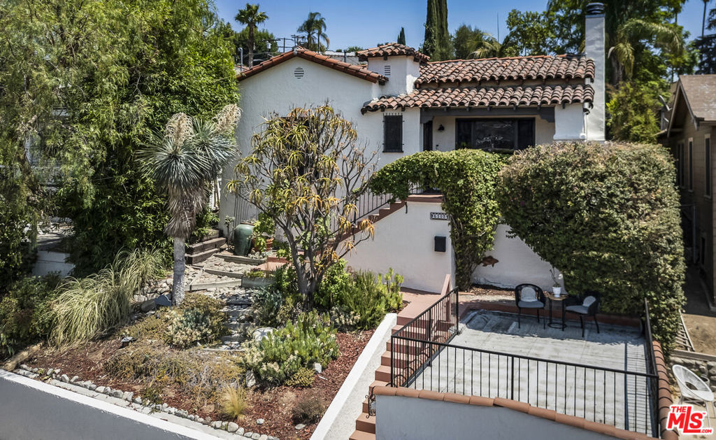 Set in the historic Mount Angelus neighborhood, this exquisite 3+2 Spanish revival showcases original architectural details at every turn. Panoramic views to Downtown LA allow glimpses of Figueroa, where iconic Frank's camera, and the Highland Park theater peek through. The front grounds are a lush tapestry of succulents, fig trees, candelabra aloe, and yucca. The front steps ascend, while wrought iron railings, entwined with bougainvillea, guide the journey to a vintage horse-knockered front door of rich stained wood. Refined Interiors, bathed in a warm golden light from dusk to dawn, feature distinctive character detail such as hardwood floors, high cove ceilings, stained wood windows, and French windows and doors. In the living room, high stepped ceilings center around a decorative fireplace with moorish-style design vents, bay window stretches from floor to ceiling, and art deco candle sconces add glamour. The dining room is magical with dazzling Moroccan pendant lamps. The kitchen is spacious with abundant counters, stained wood cabinets, and Saltillo tile floors adorned with mini Spanish tile flourishes.Renovated bathrooms highlight octagonal marble tile in the full bathroom and mediterranean blue tile in the rear bathroom. Our Lady of Guadalupe tile feature is seen in the rear bathroom and outdoor shower - she is the symbol of hope, unity, and love. Rear primary bedroom French doors lead to a sanctuary with patio, Saltillo tile, and gorgeous rear yard loaded with bougainvillea, geraniums, and cacti. The terraced garden, seating areas, spa, fountain, and outdoor shower offer respite and renewal. Close by is Highland Park's cultural hub on Figueroa, featuring Civil Coffee, Kitchen Mouse, Triple Beam Pizza, Cookbook, The Lodge, and countless other shops and eateries.