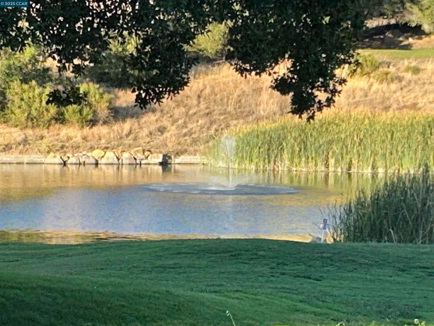 Best location and floor plan with views of the Oakhurst Country Club's 8th hole, babbling pond, waterfall and hills. This end unit's location has a large green area in front maintained by the HOA very private with no neighbors on the front side. Freshly painted with all new laminate flooring upstairs and recently new down stairs. The primary suite has sweeping views, double sinks, tub with shower and a large walk-in closet. This home is light and bright with tall ceilings including decorating niches. Kitchen has granite counters, all stainless steel appliances and plenty of storage. Open den and kitchen also opens to the patio making it a great gathering place to enjoy your friends and family and the views. Upstairs laundry closet includes washer and dryer with linen/storage cabinet directly across. Finished double car garage with opener and large storage cabinets. Power Chair Lift available for the stairs.  Open Saturday November 1   1PM to 4PM.