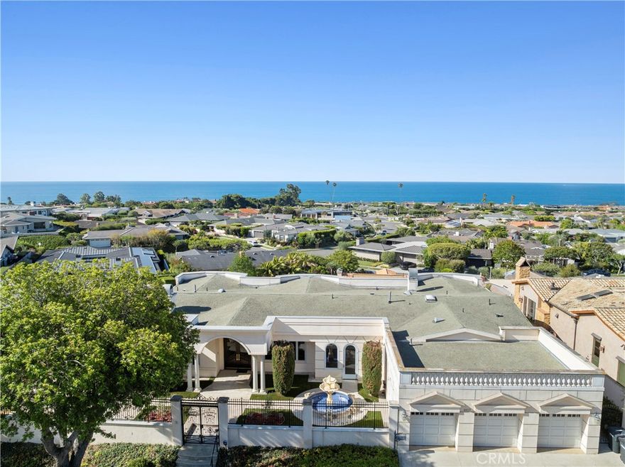 Grandeur meets coastal elegance at this gated estate, introduced by a stately fountain and dramatic entry. Inside, soaring ceilings frame breathtaking ocean views from nearly every room. Designed for entertaining, the expansive chef’s kitchen showcases granite counters, a six-burner Viking range with griddle, SubZero refrigerator, Gaggenau induction cooktop, microwave, dishwasher, prepping sink, and a spacious layout overlooking the dining area and wet bar with custom shelving, wine storage, and sprawling counters. The formal family room with fireplace and French doors offers a warm yet private retreat. Two luxurious primary suites sit at the forefront of the view, each with walk-in closets and spa-inspired bathrooms featuring jetted tubs, walk-in showers, dual vanities, private water closets, and abundant storage. Two additional ensuite bedrooms plus a mirrored gym with mobile barre functionality provide versatility and comfort. Additional features include a private laundry room, a finished 3-car garage, and a sprawling rear yard showcasing panoramic sparkling water views.