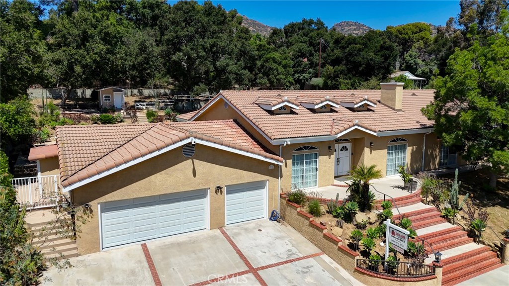 Tucked away in a quiet cul-de-sac in one of Chatsworth’s most desirable neighborhoods, this exceptional custom-built single-story home sits on a sprawling 18,000+ sq ft lot—offering the ideal layout for multigenerational living. Built in 1995, the home features 5 spacious bedrooms and 6 bathrooms, with each bedroom boasting its own private en-suite, providing comfort and privacy for extended family and guests. This rare configuration makes it perfectly suited for blended families or those seeking independent spaces under one roof. At the heart of the home is a remodeled kitchen, complete with granite countertops, stainless steel appliances, a center island, and a pantry. The adjacent family room, featuring a built-in bar, is ideal for entertaining or casual family gatherings. Additional living spaces include a formal living room with a cozy fireplace and an elegant dining room for special occasions. The expansive primary suite offers a private retreat with a fireplace, walk-in closet, and a spacious bathroom featuring a Jacuzzi tub and separate shower. Step outside to enjoy the peaceful, resort-style yard with views of the Santa Susana Mountains. The beautifully landscaped grounds include a sparkling pool, koi pond, grassy play areas with fruit trees, a charming children’s playhouse, covered patio, and multiple flat terraces perfect for gardening or creating serene outdoor seating areas. Additional features are Copper plumbing; Newer roof; Recessed lighting; Central heating & air conditioning; Fully owned solar panels. With its recent renovation, the extra-large three car garage features seamless direct access creating an exceptional space tailored for the true automotive connoisseur. With a little vision, this home can truly be the place where lasting memories are made. Some photos are virtually staged.