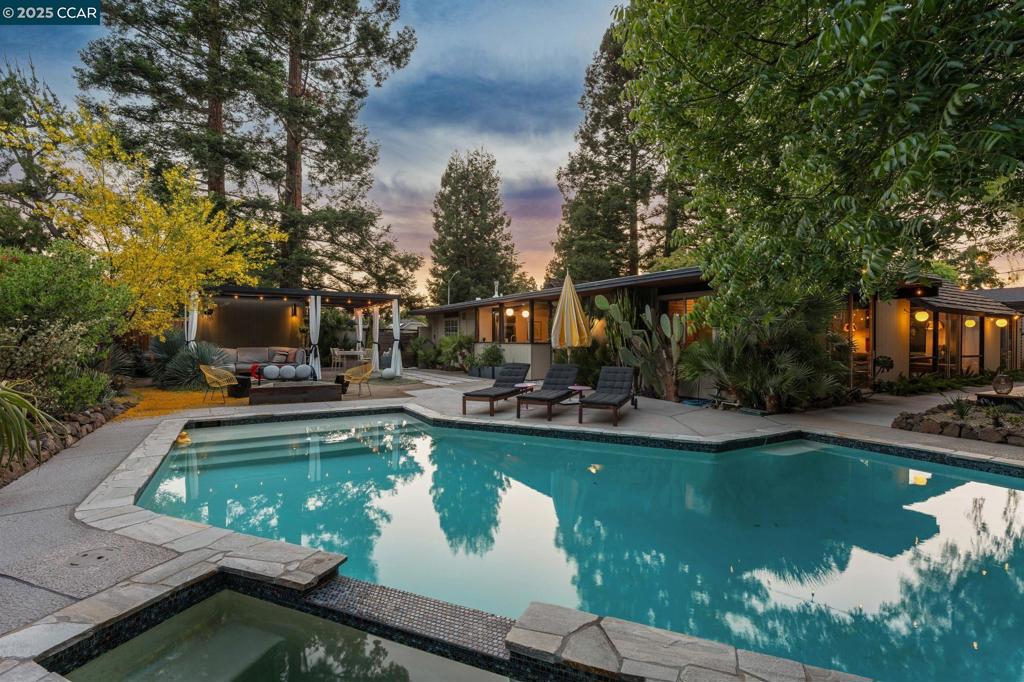 Step into this extraordinary Claude Oakland-designed Eichler home nestled in Walnut Creek’s coveted Northgate neighborhood. With it's signature open-air atrium boasting two Japanese maple trees and mature landscaping surrounding the home, this rare W-24 model is the epitome of indoor-outdoor living. Iconic globe lighting, original post-and-beam construction, and floor-to-ceiling glass showcase the home’s architectural pedigree. The updated kitchen features Thermador appliances, Sub-Zero refrigerator, quartz countertops, walk-in pantry, a spacious island, and built-in coffee nook. Updated bathrooms with double vanity, including an original Roman-style shower/tub in the primary suite. Radiant heating throughout warms toes on the polished concrete. Danish built-ins in the fourth bedroom/lounge/office and rich walnut paneling enhance the classic mid-century design of this home. A custom-built detached studio, complete with mini split, adds additional flex space. Multiple outdoor zones invite you to relax or entertain or both in your private oasis. With expansive redwood decking, lush, drought-tolerant landscaping, sparkling pool with spa, and 6 person sauna, this home is a must see. Located near shopping, trails & parks, transportation, downtown Walnut Creek and top rated schools.