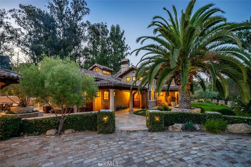 Truly unlike anything you’ve seen on the Central Coast. Inspired by the artistry and natural beauty of the Ojai Valley and craftsman stonework, this unforgettable property blends luxury, function, and style.



As you arrive, the stone-lined driveway opens to a spacious motor court with a detached five-car garage, and covered carport—perfect for RVs, trailers, or equipment. Low stone walls and manicured hedges guide you toward the main home, while to the right of the garage, a covered patio and workshop overlook a central courtyard with an outdoor kitchen, wood-fired pizza oven, built-in firewood storage, and fireplace—ideal for entertaining.



The front lawn lends a pathway to a professional-grade tennis court, complete with night lighting, viewing areas, swing-out basketball hoop, and bar. In the backyard, a built-in hot tub and cozy firepit invite relaxing evenings under the stars.



Not to be outdone, the inside this incredible home is airy and inviting, with soaring beamed ceilings, decorative windows, and custom wood-and-metal chandeliers. Concrete floors provide natural cooling, while a floor-to-ceiling stone fireplace anchors the living room space. A dedicated office and half bathroom is just off the living room—ideal for working from home or private retreat.



The chef’s kitchen features a gas range with custom hood, oversized Viking refrigerator, large center island with prep sink and seating, walk-in pantry, beverage center, and open dining area perfect for hosting gatherings. Just off the kitchen is a charming walk-through mudroom with built-in storage and windows to the courtyard.



The primary suite is a peaceful haven on the main level, complete with a walk-in closet, spa-like bath with dual sinks, walk-in shower, soaking tub, and a large slider opening to the front yard—and incredible hillside views. A cozy bonus room with fireplace opens to the backyard, while barn doors reveal a spacious laundry center with storage and folding counter.



Upstairs, a sitting area leads to two additional bedrooms, each with built-ins and private ensuite bathrooms.



Additional highlights include a detached guest studio with full bath, a small storage barn, raised garden beds, and pastureland.



Crafted with unmatched attention to detail and designed for a seamless indoor-outdoor lifestyle, this estate is more than a home—it's a sanctuary like no other.