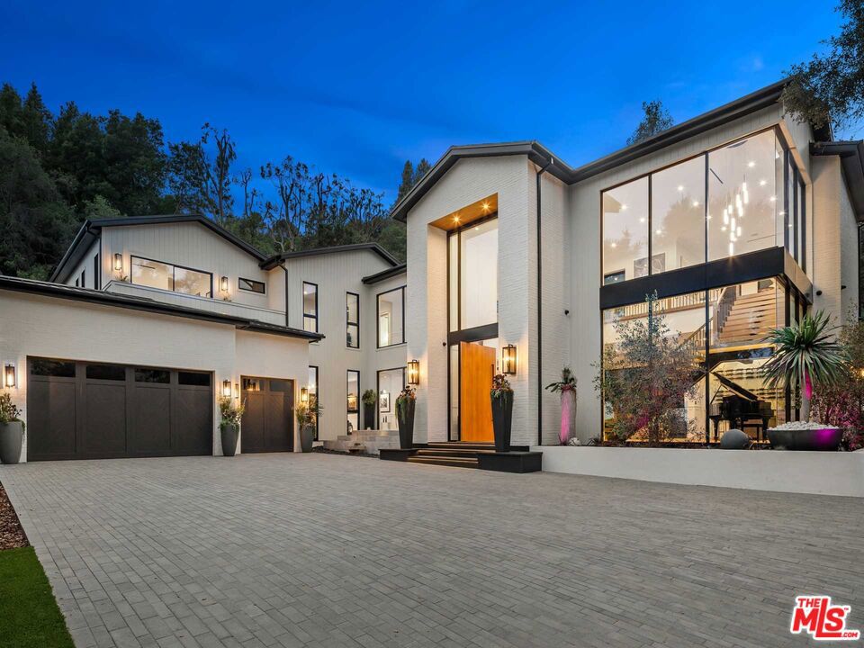 A light-filled, new construction modern farmhouse in lower Mandeville Canyon, 13158 Boca De Canon Lane masterfully blends tranquility, thoughtful amenities and inspired contemporary design. Set on a quiet private road, framed by lush foliage and past a towering oak tree, the 12,087-square-foot, six all-ensuite bedroom main house welcomes guests with a double-height foyer, a stunning floating staircase and breathtaking walls of windows. On the main level, find hardwood floors, soaring ceilings, a formal living room, a full-size wet bar, a kitchen with imported marble and two islands, a butler's kitchen and a breakfast nook that overlooks the heated pool. The second level encompasses a lounge area with a wall of pocket doors that disappear to reveal a serene open-air terrace. Also on the second level are four bedrooms and a grand primary suite, which is complete with two private balconies, a marble-lined and book-matched fireplace, an oversized spa-like bath with dual vanities, a soaking tub, an expansive steam shower and a boutique-like custom walk-in closet with built-in storage. This home's bountiful amenities are designed for everyday comfort and effortless, all-season entertaining and include a covered outdoor cabana, a dining area with a pizza oven and barbecue, a movie theater, a sports court, a mini putting range, a gym and a dry sauna and steam room. Additional features include an onsite two-bedroom, one-bath guest house with kitchenette and a three-car garage. A true Westside gem, 13158 Boca De Canon Lane is just 10 minutes from Brentwood's most popular restaurants, shops and cafes, and less than 20 minutes from Santa Monica's beaches.