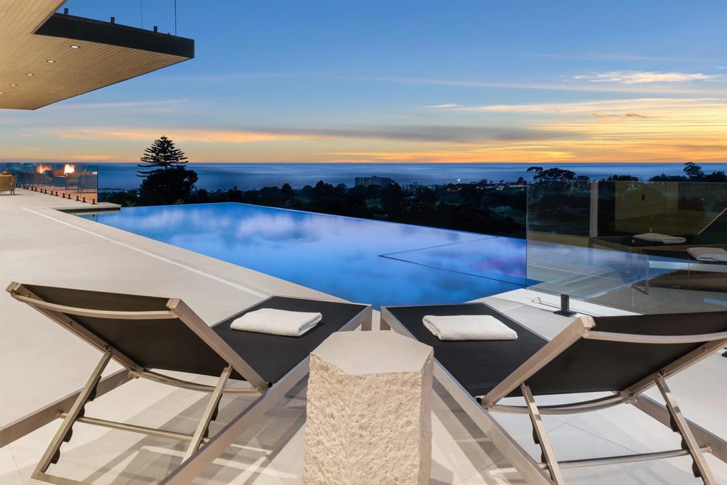 Elegantly situated in the prestigious Muirlands community, this brand-new contemporary masterpiece boasts some of the most breathtaking, sweeping views of the Pacific Ocean, golf course, and city skyline—truly among La Jolla’s most extraordinary vistas. Step inside to discover seven spacious bedrooms, each thoughtfully designed with its own en suite bath, including two luxurious primary suites, one on each floor, offering ultimate privacy and comfort. Every detail has been meticulously curated to embody sophistication and ease, from the Wolf kitchen appliances and Sub-Zero refrigerator to the expansive walls of glass that frame stunning views and seamlessly blend indoor and outdoor living. Two laundry rooms, an elevator, and a 4+ car tandem garage ensure that convenience meets grandeur at every turn. Outside, entertain in style by gathering around the fire pit, firing up the built-in BBQ, or taking a refreshing dip in the gorgeous infinity-edge pool where the horizon feels within reach. A dedicated game room and guest suite add layers of versatility to this elegant home. More than a residence, this is a statement of modern luxury and tranquility; a true sanctuary nestled in the heart of La Jolla. A rare and remarkable opportunity to own one of the most exceptional properties in the coveted Muirlands community awaits.