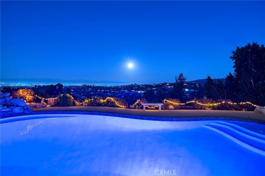 Tucked away in the hills of Tarzana on a desirable corner lot in a peaceful cul-de-sac, this beautifully maintained home offers spectacular 180° views of sparkling valley lights, rolling hills, and majestic mountains. From golden sunrises to tranquil moonlit evenings, every moment here is surrounded by natural beauty—an ideal setting for relaxed living and unforgettable entertaining. Step inside to an open, light-filled layout featuring a formal dining area, a spacious living room with fireplace, and a bright kitchen with a center island, new double oven, new Insta-hot, and effortless flow into the family room—where walls of windows showcase breathtaking views. Downstairs includes a flexible bedroom and full bath, plus a bonus room perfect for a home gym or extra space. A striking spiral staircase leads to an airy upstairs landing with near floor-to-ceiling windows that flood the space with natural light and welcome in cool breezes. The large primary suite offers a peaceful retreat with a large walk-in closet, soaking tub, and separate shower. Three additional bedrooms and a full bath complete the second floor - two of which also take full advantage of the stunning views. Outdoors, enjoy your own private oasis: a sparkling pool with waterfall, gated area for kids, pets or BBQs, and a large side yard ready for sport/pickleball or even more entertaining space. Have fun watching the Fourth of July fireworks light up the city skyline near and far! Recent upgrades include: newer roof/rain gutters, HVAC, water heater, pool plaster/tile/pump, attic fan, dual-pane windows, smooth ceilings, recessed lighting, kitchen sewer line (replaced), exterior sewer line (lined) & copper pipes throughout the home interior. Located near top-rated schools and offering ample guest parking, this rare gem combines comfort, lifestyle, and an unbeatable location. Don’t miss your chance to make it yours!