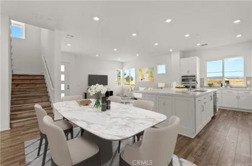 Welcome to modern luxury in the heart of Five Point Valencia. This stunning Lennar Rosemist Plan 4, the largest and most desirable model in the community, was completed a couple years ago and offers the perfect blend of sophistication, comfort, and style. With five bedrooms, four and a half bathrooms, and three spacious levels, this home showcases impeccable design and attention to detail. The main floor features an open-concept, dining area, and chef’s kitchen with a large quartz-topped island, professional-grade stainless steel appliances, and a six-burner cooktop with designer hood. Ten-foot ceilings and wood-like LVP flooring create a sense of warmth and grandeur throughout. A guest bedroom with a full bath on the first floor provides flexibility for visitors, extended family, or a home office. Upstairs, the luxurious primary suite offers a peaceful retreat with a spacious walk-in closet, dual vanities, soaking tub, and separate shower, while three additional bedrooms, two more baths, and a laundry room complete the second floor. The top level is a versatile bonus/loft area featuring its own bathroom, wine fridge, counter space, and a covered terrace with panoramic views of the Santa Clarita Valley—perfect for a game room, gym, or lounge. Enjoy year-round outdoor living with a gated backyard and covered patio ideal for dining or relaxing. Located within the vibrant Five Point community, residents have access to world-class amenities including three pools, a spa, BBQ areas, playgrounds, scenic greenbelts, and a resort-style clubhouse. Conveniently close to shopping, restaurants, top-rated schools, Magic Mountain, and freeway access, this like-new home offers the best of modern design and community living in one of Valencia’s most desirable neighborhoods.