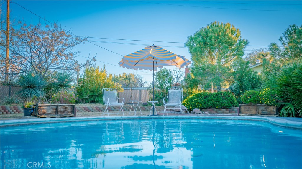 Located in the highly sought-after Sky Harbor area of Yucca Valley, this updated and stylish 3 bedroom, 2 bath POOL HOME offers a perfect blend of space, comfort, and desert luxury on a generous 0.8-acre lot. The expansive living room features a charming brick hearth fireplace, large windows that fill the space with natural light, and an open flow into the informal dining area, where French doors lead directly to the outdoor living space. The kitchen is a chef’s delight with granite countertops, a full backsplash, plenty of warm wooden cabinetry, and a convenient breakfast bar. A large formal dining area has its own outdoor access, making it ideal for entertaining. Each of the bedrooms is generously sized and well-lit, while the guest bathroom features tile counters and a tiled walk-in shower. The primary bedroom enjoys an attached bath which is finished in matching tile as well as having its own walk-in shower, offering both function and a touch of luxury. Step outside to enjoy the exceptional outdoor living space. Covered porches in both the front and back provide shaded retreats, while the backyard is a true oasis with a sparkling in-ground pool, paved patio, hot tub, mature landscaping, a shade pergola, and multiple seating areas for relaxing or gathering with friends and family. With its modern updates, inviting layout, and resort-style backyard, this Sky Harbor home captures the best of desert living.