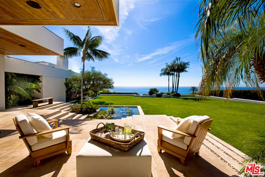 A spectacular contemporary estate in the heart of Malibu. Situated on a private bluff at the end of a gated tree-lined driveway. Enjoy sweeping ocean views from the moment you enter the foyer and stare down the grand hallway. A peaceful interior offers Beaumaniere stone floors, dark wood, and walls hand-finished in white venetian plaster. This resort-like compound features a state of the art lighted tennis court, gym, 4-car garage, staff quarters, a guest-suite with its own entrance, and 6 luxurious bedrooms, including a his and hers master suite with a massage room, retreat, spa and fireplace. Perfect for casual indoor-outdoor living, with an abundance of space for entertaining. Pocket doors throughout open to a, tropical landscape complete with a pool, spa, bbq, terraces, and a beautiful grassy yard with a private steps leading down to Malibu Road.