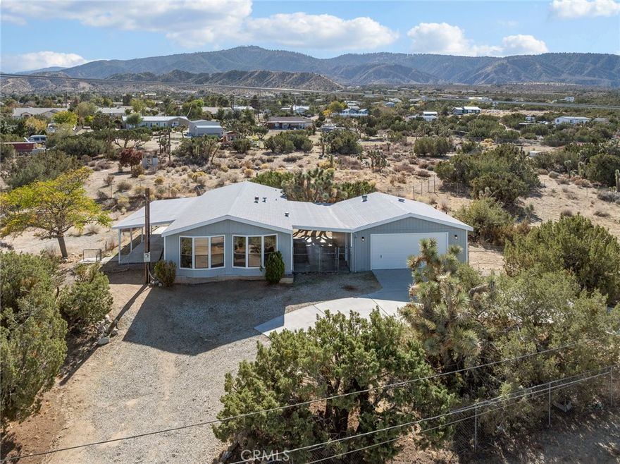 Newly remodeled and renovated throughout! This manufactured home feels brand new and offers a view of the valley to the north and the mountains to the south with its preferred Southside Pinon Hills location.  The home has 3 bedrooms and 2 baths on a spacious 2.05 +/- acre property that is fully fenced and offers 1,344 +/- square feet for the entire family. This property has just been updated with new paint inside and out, new flooring throughout with luxury vinyl in most of the home and carpet in the bedrooms, brand new kitchen with modern wood cabinets white quartz counters, and stainless steel appliances. Additionally, the bathrooms have been updated with the primary bath offering dual vanities both bathrooms offer new, modern fixtures. The property has is oversized and has chainlink fencing. The detached garage is an oversized 2 car garage and is connected by a covered breezeway making access convenient. The property is located a not too far from paved road and offers a great location with very quick access to town and schools. The property is zoned for horses and located within the Snow Line School District.