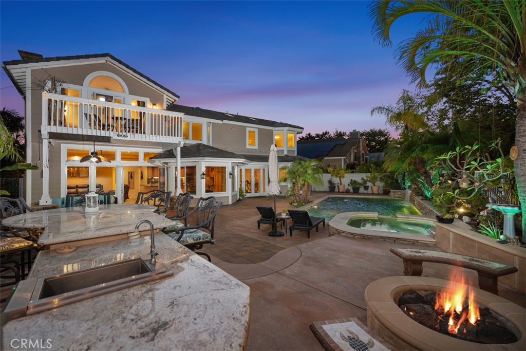 Experience luxury living at 8 Eastridge, a distinguished home with a private backyard oasis in the sought-after Oakmont community of Coto de Caza. Situated on an expansive lot, the property features a sparkling pool, spa, built-in BBQ, and plenty of outdoor space for both relaxation and entertaining. This unique residence offers a highly desirable floor plan with 5 bedrooms plus an office and 3 bathrooms. The open-concept design is enhanced by high ceilings and multiple skylights that bring in an abundance of natural light. Upon entry, a formal living room welcomes you with a full wet bar, accompanied by an adjacent office or bonus room enclosed with French doors. The gourmet kitchen is outfitted with stainless steel appliances, a built-in gas range, double ovens, granite countertops, and a breakfast nook. It flows seamlessly into the family room, with a formal dining area nearby, perfect for hosting. A convenient downstairs bedroom and full bathroom offer flexible living arrangements, and the office can easily be converted into a sixth bedroom with the addition of a closet. Upstairs, the serene primary suite includes a well-appointed bathroom with dual sinks, a vanity area, soaking tub, and separate walk-in shower. Three additional spacious bedrooms and another full bathroom provide ample space, with one of the bedrooms offering access to a private balcony overlooking the backyard. Outside, your tropical oasis includes a pool and spa with a waterfall feature, outdoor shower, fire pit, and a built-in BBQ with counter seating, ideal for al fresco dining. Additional upgrades include newer flooring and garage door, an upgraded spa with jet booster pumps, owned solar panels, and Bluetooth-enabled backyard speakers. Enjoy access to the many amenities offered by Coto de Caza, including the Golf and Racquet Club (optional memberships available), equestrian facilities, scenic hiking trails, and more. Don’t miss the opportunity to own this exceptional property that blends comfort, space, and California lifestyle.