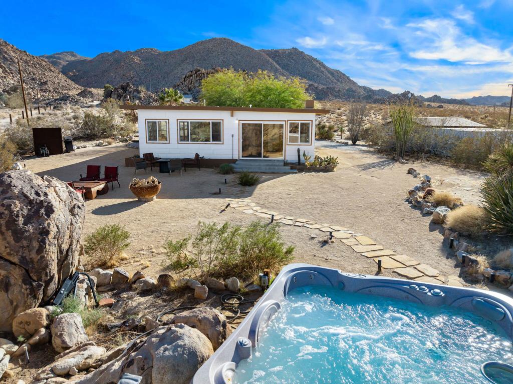 Tucked into the rolling hills of Joshua Tree, surrounded by massive rock formations and native desert flora, La Luna Azul offers a rare opportunity to own a private sanctuary in one of Southern California's most sought-after destinations. This thoughtfully designed contemporary home blends modern elegance with the rugged beauty of the high desert, providing an exceptional living experience just minutes from Joshua Tree National Park and a short walk to the famous Kellogg Doolittle house.Expansive windows frame breathtaking views in every direction, filling the home with natural light and seamlessly integrating the indoor and outdoor environments. The open-concept living area features polished concrete floors, a spacious seating area, and a cozy fireplace, creating a warm yet refined atmosphere. The full kitchen and dining area provide the perfect space for entertaining or enjoying quiet meals with views of the surrounding landscape.The home's two well-appointed bedrooms offer privacy and comfort, with a king-sized bed in the primary suite and a queen-sized bed in the second bedroom. A thoughtfully designed bathroom completes the interior, ensuring a balance of style and functionality.Outside, the property is designed to embrace the desert's natural beauty. Multiple lounge areas provide ideal spaces to unwind, whether enjoying coffee at sunrise or a cocktail at sunset. A hot tub, seamlessly integrated into the boulders, offers a serene retreat for relaxation and stargazing, while the outdoor fire pit and built-in BBQ create a perfect setting for entertaining under the vast night sky.La Luna Azul is more than a home--it is an experience, offering unparalleled privacy, modern design, and a deep connection to the natural surroundings. Whether as a primary residence, vacation home, or investment property, this extraordinary retreat captures the essence of desert living at its finest.For more information or to schedule a private showing, contact us today.
