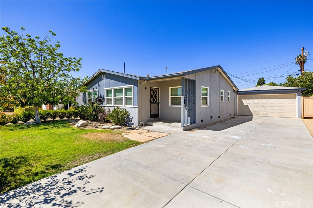 Single-story home set on a spacious lot with endless potential. The front yard features manicured landscaping with a river rock wall, planters, and mature trees. A covered front porch welcomes you into a bright entryway and family room with a large picture window overlooking the yard. Rich laminate wood flooring extends through the main living areas. The living room includes a built-in niche and sliding glass door to the back patio, while the updated kitchen offers granite countertops, tiled backsplash, refinished cabinetry, and a breakfast nook with front yard views. A convenient laundry closet and half bath are located just off the kitchen, with direct access to the driveway and garage. The home includes three bedrooms and a full hall bathroom featuring tiled counters, a walk-in shower with glass enclosure, and a separate tub. The enclosed covered patio provides additional living space and could easily be reopened as a traditional patio. The expansive backyard offers a large grass area, room for gardens, and space to add a pool or even an ADU. The home does offer a newer HVAC system.