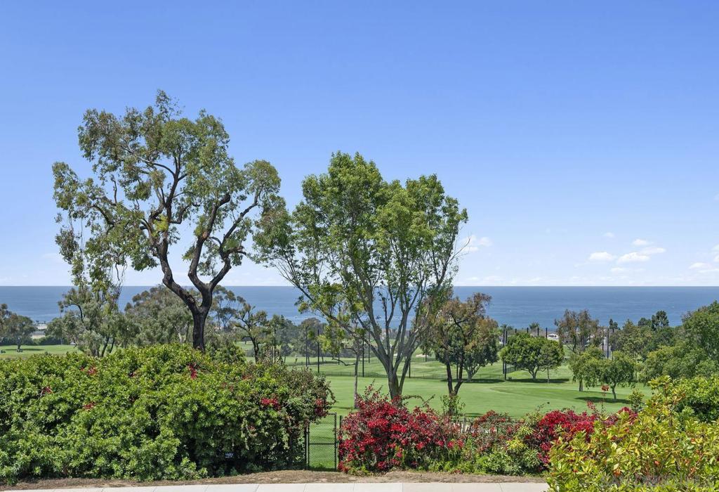 With stunning views across the fairways of La Jolla Country Club to the Pacific, this beautifully-designed home is situated on an exceptional lot along prestigious Fairway Road. Past the covetous circular driveway lies a meticulously-maintained home bathed in natural light. Soaring ceilings, expansive windows, and functional design create both a voluminous and welcoming atmosphere. An ideal floorplan features four spacious ensuite bedrooms, separate dining and living rooms, and an impressive library/den- with rich wood paneling, high ceilings, and cozy fireplace. The lovely primary suite offers stunning views, a large walk-in closet, and bath with skylights and numerous windows. An adjacent office overlooks a serene backyard waterfall. Expansive private patios offer numerous spaces for entertaining and relaxation with mature trees and vibrant landscaping. An upper flat garden area would be perfect for a future pool/cabana, sports court, or even a guest house with views. This special property combines timeless design, versatile outdoor spaces, and striking views to create a wonderful opportunity in La Jolla.