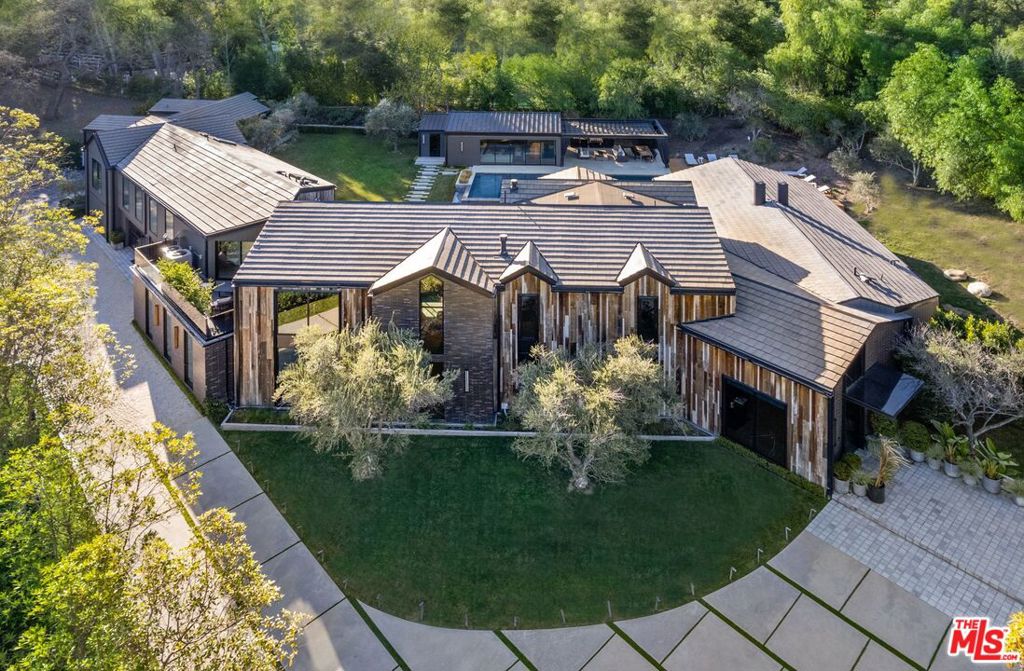 AUCTION BIDDING OPEN: Bidding ends 4/30. Previously Listed $17.495M. Current High Bid $12M. No Reserve. Showings Daily By Appt. Welcome to this luxurious, modern farmhouse retreat in the ultra-coveted Hidden Hills community. Set on an acre and a half at the end of a private cul-de-sac in the guard-gated community, this estate offers the ultimate in privacy and security. The home's unique architecture, designed by Nobel LA, offers the best in indoor/outdoor living. The interior features double-vaulted wood ceilings, glass walls, and opulent details, such as the bespoke brass fireplace and dual Preciosa chandeliers. The stunning primary suite offers a fireplace with a sitting area, a designer walk-in closet, and a spa-like bathroom with dual chiseled stone vanities, a steam shower, and a soaking tub. The principal residence and a separate guest house are surrounded by an outdoor oasis offering a large flat lawn, a hardscape outdoor entertaining area, and a 65' swimming pool with a spa. Poolside cabana with indoor sitting area/game room, bathroom, built-in BBQ, fire pit, and video wall. Additional amenities include a home theater and fitness/music studio. Nestled within the tranquil Hidden Hills, this exquisite modern farmhouse retreat is not just a home; it's a testament to luxury living at its finest.