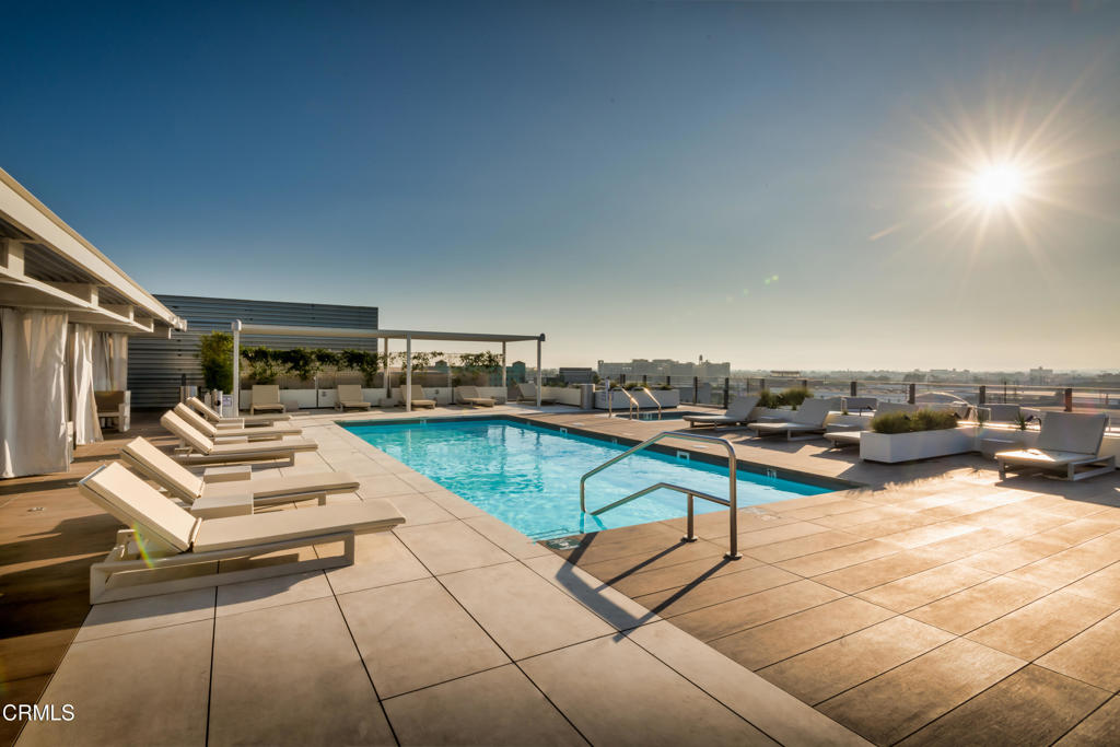 Spacious and filled with natural light, this open-style loft boasts soaring ceilings and a dramatic wall of floor-to-ceiling double-pane windows framing panoramic views of the iconic Downtown LA skyline. Situated in the highly sought-after Barker Block, the residence offers exceptional versatility and style. A custom-built wardrobe enhances the bedroom alcove, while the large bathroom features an oversized soaking tub and stackable in-unit laundry. The gallery kitchen is equipped with stainless steel appliances and generous cabinetry, perfect for both everyday living and entertaining.The open-concept layout easily accommodates multiple zones--whether you envision a home office, formal dining area, or inviting living space. Additional highlights include one gated, covered parking space and 24/7 on-site security. Residents enjoy access to a resort-style rooftop with a heated pool, spa, fitness center, BBQs, and fire pits--ideal for relaxing or hosting friends. All of this is just steps from acclaimed restaurants, coffee houses, museums, and galleries, as well as The Arts District Park. Conveniently close to major freeways, metro stations, and train lines, this loft offers the perfect balance of vibrant city living and modern comfort.