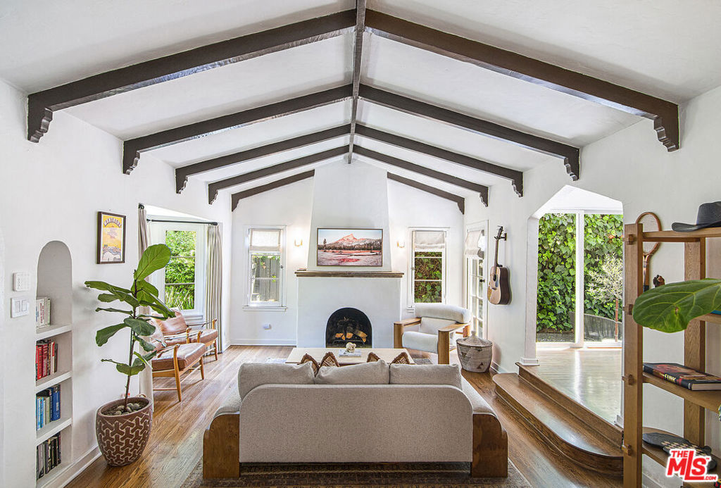 STYLISH SPANISH BUNGALOW IN BEVERLY GROVE. Enter this fabulous pied-a-terre in the heart of Beverly Grove through a gated and hedged front garden into a grand step-down living room with vaulted, beamed ceiling, bay window and fireplace. The formal dining room with sliding glass doors opening to a private patio and outdoor lounging area adjoins a beautifully remodeled chef's kitchen with quartz counters, pantry, Thermador stove with vented hood, Bosch stainless steel appliances, and a Blanco cast iron farm sink. A luxurious primary suite provides direct access to the outdoor patio and boasts a vaulted ceiling, walk-in closet, fully remodeled bath with a large marble shower and soaking tub, and dual vanity. Additional features include a generous ensuite guest bedroom, additional powder room, central AC, Nest thermostat, multiple skylights, hardwood floors, crown moldings, custom window-coverings, private driveway with EV charger, ideal location steps from dining and shopping on Third Street, the Grove, the Beverly Center and Melrose. LAR2 Zoning may allow for additional living space.
