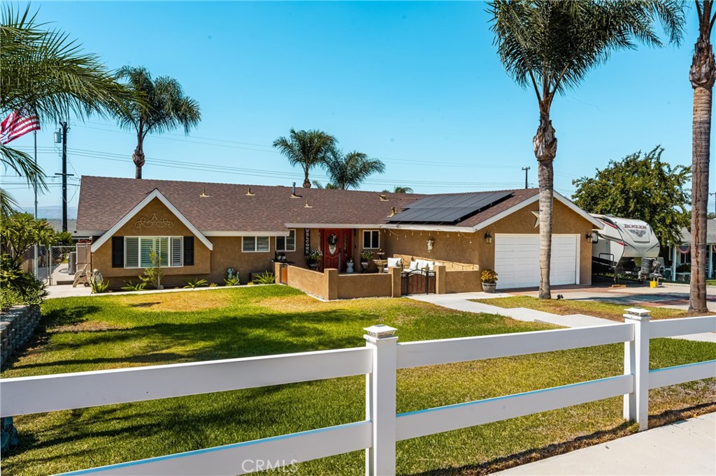 Convenience, technology, and style come together seamlessly in this Norco gem—where no detail has been overlooked. From the white picket fence and custom-gated front porch to the welcoming family room and covered outdoor living space, this home is designed to live well.
Inside, a formal entry opens to a living room with a fireplace. The remodeled kitchen is enjoyable, boasting bright white cabinetry, stone countertops, and an oversized custom island built for gathering. Multiple dining areas, including a charming breakfast nook and an open dining room with white beam ceilings, make entertaining effortless. The private primary suite features an on-trend barn door entry to the updated bath, while three additional bedrooms enjoy abundant natural light from large vinyl windows. Recent updates extend to comfort and efficiency with a newer HVAC, tankless water heater, and fully paid solar installed with the recent roof. Don’t miss the flexible bonus space—currently styled as a playroom but easily to convert into an office or personal gym space. Step outside to your year-round retreat: a sparkling dual-level pool and spa enhanced by a brand-new retaining wall and fresh concrete surround, plus a built-in BBQ and wrap-around patio. Whether it’s summer fun or evening gatherings, this backyard is ready for it all. Bonus perks include a gated RV space for toys, plenty of storage and PAID SOLAR. This home checks every box—style, upgrades, energy savings, and lifestyle. Don’t wait—this one is move-in ready and waiting for you!