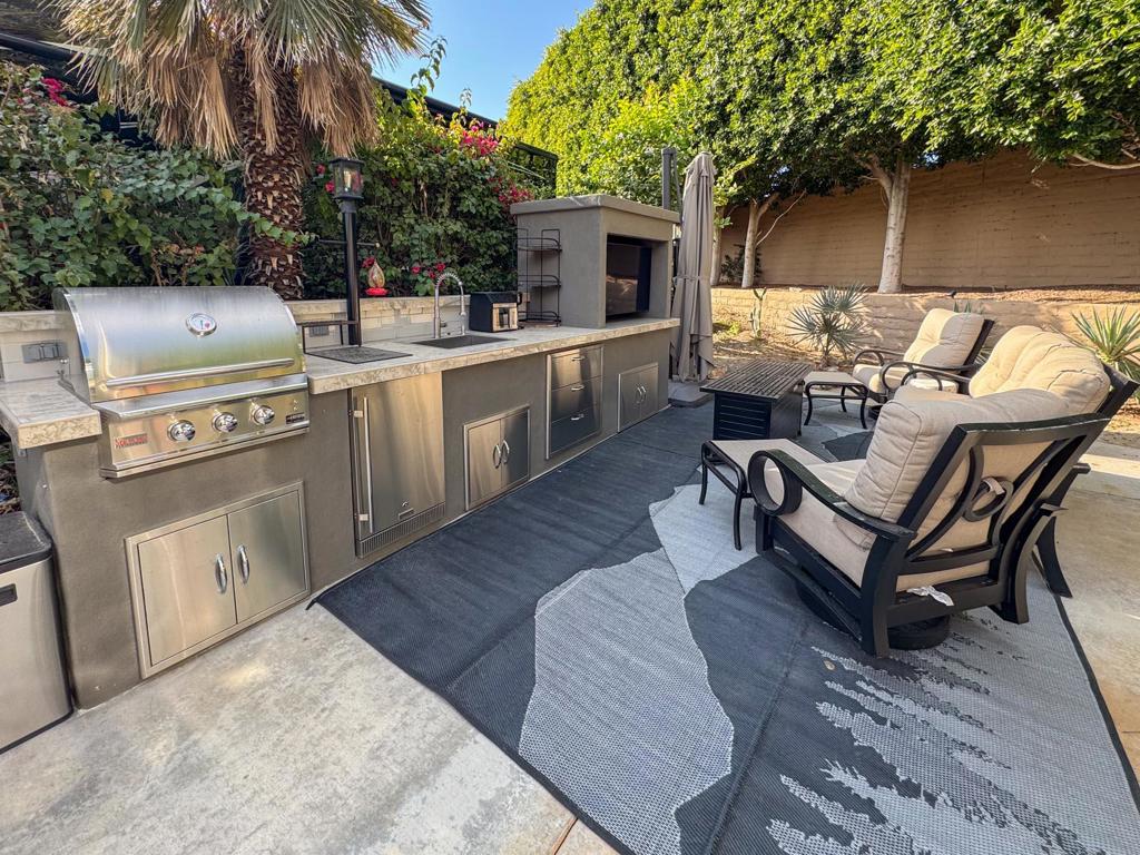 Step into your private landscaped retreat. Oriented to capture the morning sun and afternoon shade, this beautifully appointed lot offers a tranquil yet functional space for both relaxation and entertaining. The remodeled kitchen (2022) brings modern convenience to your outdoor lifestyle, featuring a built-in BBQ, convection cooktop, sink, refrigerator, and ample storage drawers for effortless hosting. Golfers take note--you are just steps away from two golf course entrances, making it easy to hit the greens whenever you please.Enjoy the ultimate outdoor living experience with a built-in 50' TV, plush seating, two swivel chairs with ottomans, and a dining table for four, all centered around a stylish coffee table/fire pit and shaded by a large cantilever umbrella. Custom furniture covers ensure long-lasting protection, while the included golf cart with new batteries and tires adds even more convenience. This furnished luxury RV lot is the perfect blend of comfort, style, and resort-style living.‍