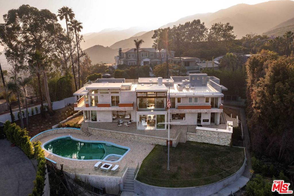 Perched behind gates with sweeping ocean and city views from the entire Santa Monica Bay to Downtown, this striking architectural estate - designed by acclaimed architect Anthony Zubick, AIA - offers the ultimate in California luxury living. Walls of Fleetwood pocket doors vanish to reveal panoramic ocean and city vistas from nearly every room, blurring the line between indoors and out. The open layout was crafted for a balance of both everyday comfort and entertaining, with a chef's kitchen outfitted with top-tier Wolf and Miele appliances that flows into expansive living and dining areas. A sculptural floating staircase leads to the upper level, home to four secondary bedrooms and a stunning primary suite with dual walk-in closets, a spa-like bath, and a wraparound terrace made for taking in the dramatic scenery. The flat backyard is equally impressive, featuring a pool, spa, outdoor kitchen, fire pit, and lush landscaping - ideal for hosting gatherings large or small. Additional features include a three-car garage and a rooftop observation deck with jaw-dropping 360-degree views. A rare lease opportunity that embodies elevated design, privacy, and the best of coastal L.A. living.