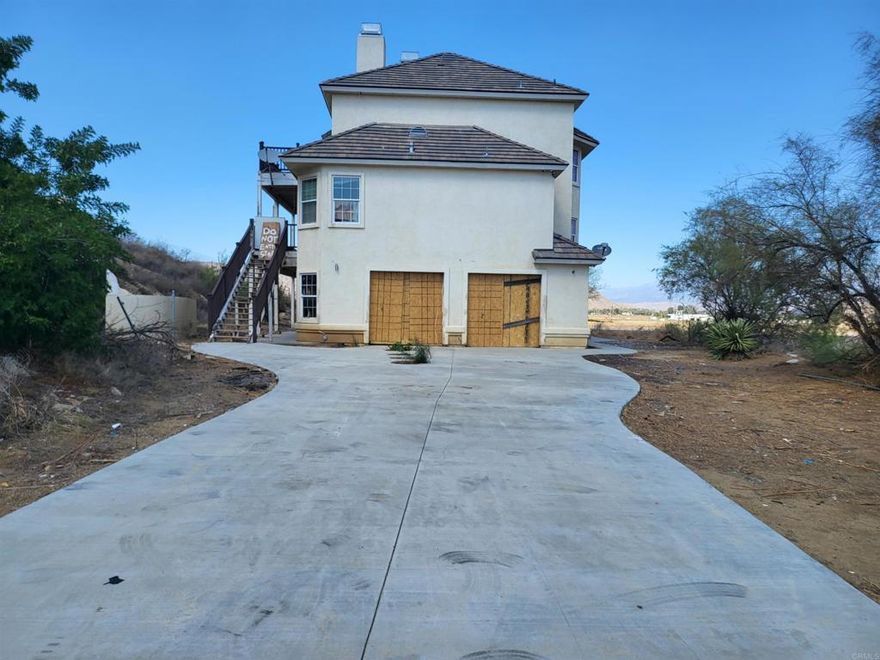Rare contractor or investor special in rural Hemet on 2.4 acres with panoramic hillside views! This 3,643 sq ft, 3-story estate home offers incredible potential for the right buyer. Privately located at the end of the street, the property features 3 bedrooms, 2.5 baths, a 4-car attached garage, an in-ground pool with a custom slide, spacious decks on the 2nd and 3rd levels, and a long driveway perfect for RVs, toys, or multiple vehicles.  Built in 2007, the home has great bones and an open layout, but it requires a full rehab a prime fixer opportunity to build value and equity. The lower-level living room offers conversion potential into a game room, extra bedrooms, or even an attached ADU.  Due to its condition, the property will not qualify for traditional financing. Located just minutes from the 215 Freeway, Winchester, Diamond Valley Lake, and other fast-growing communities. Customize this home into your private oasis!