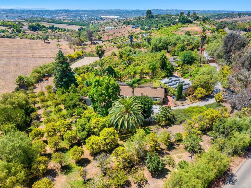 Equestrian Estate with Detached ADU - SEE VIRUTAL TOUR FOR MORE PHOTOS Located in the highly desirable West Bonsall, CA area with wonderful coastal breezes and minutes from local beaches, this Original Owner/Builder Equestrian property spans 3.1 acres of fully fenced and gated land. The primary residence is a single-story home built in 1997, approximately 2,660 sq. ft. with four bedrooms and four full bathrooms. It features a 336 sq. ft. subterranean bonus area suitable for various uses such as a guest suite, playroom, or additional storage. The master bedroom/retreat includes a gas wall fireplace, walk-in closet, and an opulent spa-style bath. The interior flooring primarily consists of Hickory/Pecan with Acacia flooring in the primary and small east bedroom, and color-matched oak in the west bedrooms. Other features include three gas fireplaces, the heart of the home, granite chef’s kitchen equipped with high-end appliances and a walk-in pantry, dual-zoned heating and air conditioning, a tankless water heater, Owned solar panels for energy efficiency and a Natural Gas home without the need for propane tank(s). External amenities include a black bottom saltwater pool with jacuzzi, pool slide, barbecue area, outdoor fire pit, all surrounded by landscaped grounds with various trees including swaying palms, a Coastal Redwood, 100 Orange, 22 Macadamia, 9 Pomegranate, 36 Olive, 24 various fruit trees, and 60 Hass avocado trees. Equestrian facilities consist of two horse stables with potential for expansion. One covered structure that houses two 12x12 covered stalls with each having an attached 18’ x 36’ outside stall: a 48’ dia. round pen, a self-draining "wash rack," and a 60’ x 155' long riding arena. The terrain across the 3.1 acres is suitable for training and turnout. A 1,200 square foot detached industrial-grade four-car garage includes a workshop and workstation supporting hobbyists or automotive enthusiasts. The property features a 900 ft. Well system/w filtration @60 GPM, with a 5000-gallon storage tank for irrigation and potable water. Additionally, the property includes a detached one-bedroom, one-bath Accessory Dwelling Unit (ADU) constructed in 2006, offering 650 sq. ft. of living space plus a 100 square foot sunroom, suitable for guests or rental income. (currently used as an office space) This estate provides privacy, ample space, and comprehensive amenities for country living while being located minutes from local beaches.