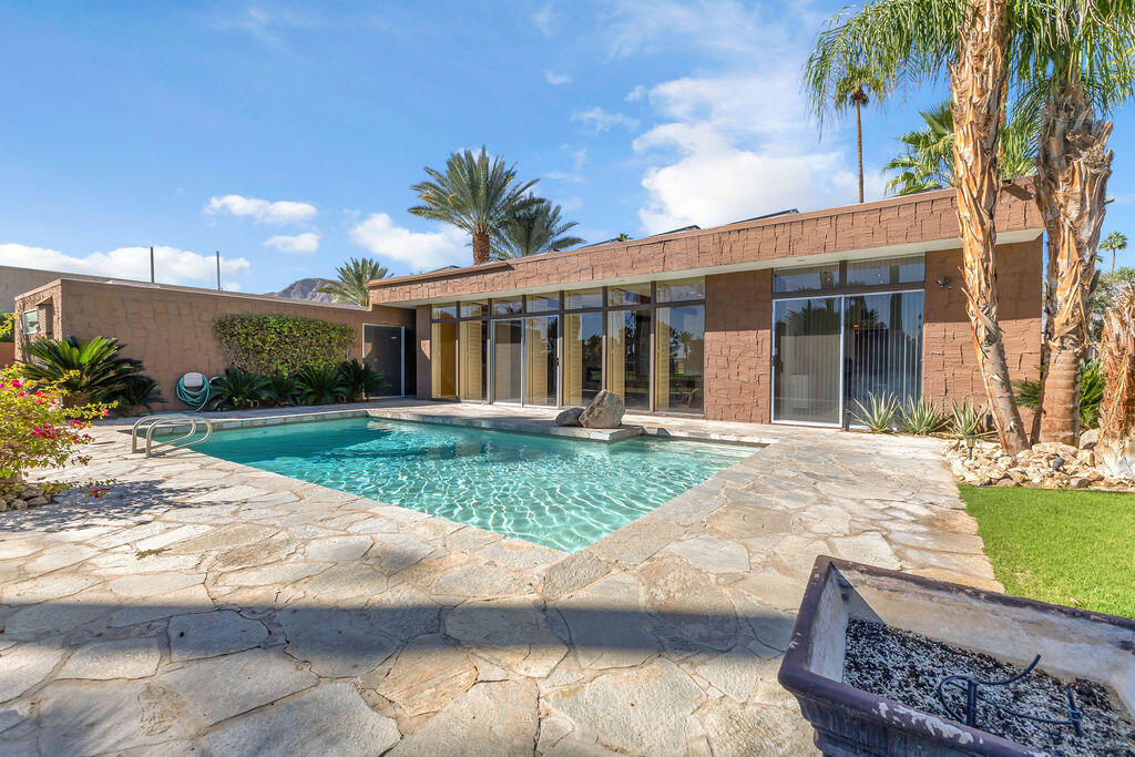 There's a certain stillness to Tamarisk West--a mid-century enclave where the hum of the desert softens into quiet, and sunlight moves through walls of glass like a living thing. Along the fairways of the storied Tamarisk Country Club, this 3,100-square-foot residence captures that sense of calm elegance that defines life in Rancho Mirage.Inside, light and landscape take center stage. Floor-to-ceiling windows and sliders erase the boundary between indoors and out, drawing the eye toward an ever-changing canvas of green fairways and mountain silhouettes. In the living room, a step-down wet bar nods to the home's architectural heritage--an invitation to linger, to pour, to enjoy the simple luxury of good company and open space.The kitchen feels generous and grounded, blending professional-grade appliances with effortless functionality--crafted for the way we live now, where cooking, conversation, and connection flow together. Each of the three bedrooms is a private haven with its own en suite bath and walk-in closet, while a dedicated office offers space to create, to focus, or simply to pause.Beyond the glass, the desert's rhythm continues--a private pool shimmering beneath a vast blue sky, framed by curated landscaping and the quiet expanse of the Tamarisk course beyond. Solar power lends the home a thoughtful touch of sustainability, marrying modern intention with timeless ease.At Tamarisk West, life unfolds without hurry. The architecture, the light, and the landscape all conspire toward one idea: serenity made visible.