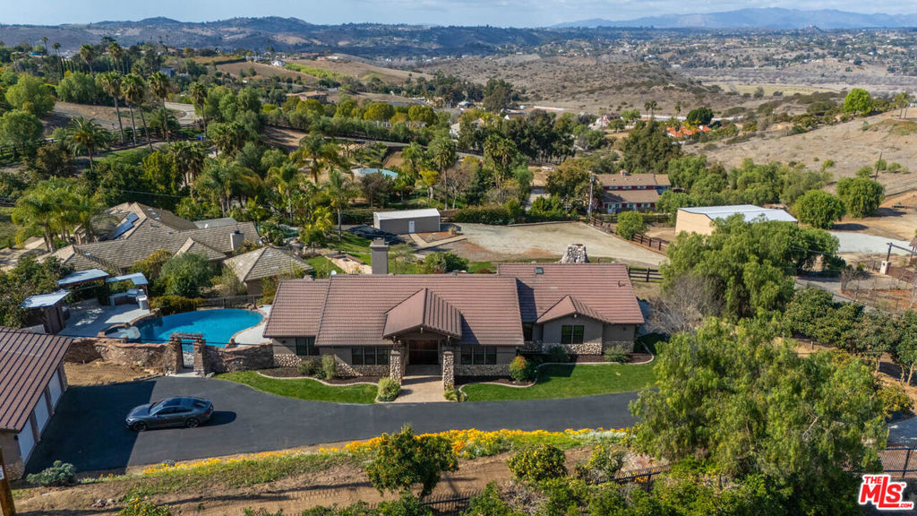JUST COMPLETED: There are no better words when buying a new home, than 'turn-key'. Nestled in the serene hills of Bonsall, and bathed by the famous "Bonsall Breeze" with 180 degree sweeping views. This stunning 4-bed, 3-bath, has just been fully renovated and boasts over 3,100 sqft of San Diego County lifestyle sitting on a private 2.5-acre lot fully gated in rod iron and three entries on to the property. The exquisite gate guides you to a beautifully landscaped entry with a craftsman style stone and stucco entry. Inside, a grand solid wood front door opens to incredible sightlines through French doors leading to the breathtaking views. The open-concept design seamlessly blends the living, dining, and kitchen areas, featuring vaulted ceilings, recessed lighting, and a cozy fireplace. The chef's kitchen presents itself with a massive polished concrete island with seating, a coffee bar and nook, state-of-the-art stainless steel appliances, a Wolf 8-burner gas stovetop and in wall faucet. The primary suite offers vaulted ceilings, patio access, a large walk-in closet with built-ins, and a spa-like ensuite with dual rain showerheads, dual vanities, and a separate W/C. The additional bedrooms are spacious, with ceiling fans and ample storage. The large laundry room includes extra cabinetry, a sink, and folding space. The backyard is an entertainer's paradise with an infinity pool, spa, sauna, outdoor kitchen, stone fireplace with built-in grill, and a pergola-covered seating area. A wraparound patio offers multiple spaces for relaxing and entertaining while enjoying the peaceful surroundings. A spacious 3-car garage completes this luxurious retreat. With plenty of room for expansion and zoned for horses. The perfect blend of coastal country living with just a 20 minute drive down to the beautiful beaches of Oceanside and Carlsbad.