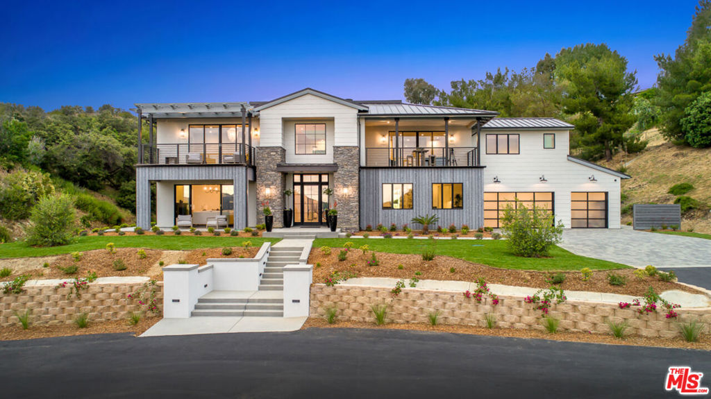Nestled within the scenic rolling hills of Calabasas, this exquisite modern farmhouse redefines luxury living. Spanning over 2 acres of lush, flourishing land, this estate seamlessly blends contemporary elegance with natural beauty, offering an unforgettable retreat. From the moment you step into the striking foyer, you're captivated by the soaring volume ceilings, an abundance of natural light pouring through expansive windows, and the warmth of wide-plank white oak floors that flow throughout the home. The formal living room exudes sophistication, while the superb office space and inviting great room are anchored by a sleek, modern fireplace. The state-of-the-art kitchen is a chef's dream, boasting top-of-the-line Thermador appliances, a subway tile backsplash, shiplap accent walls, and a butler's pantry that conveniently opens to the outdoors; perfect for effortless year-round al fresco dining. Upstairs, discover three generously sized en-suite bedrooms and a versatile bonus room with an attached balcony. The primary suite is a true sanctuary, offering breathtaking views of the surrounding hills. The spa-inspired master bath features dual walk-in closets, a soaking tub, and a stunning double-sided shower that epitomizes luxury. The rear grounds are an entertainer's paradise, complete with a cabana featuring a private bathroom, an outdoor grill station, and a sparkling pool and spa. Whether hosting gatherings or enjoying quiet evenings under the stars, this property is designed for seamless indoor-outdoor living at its finest.