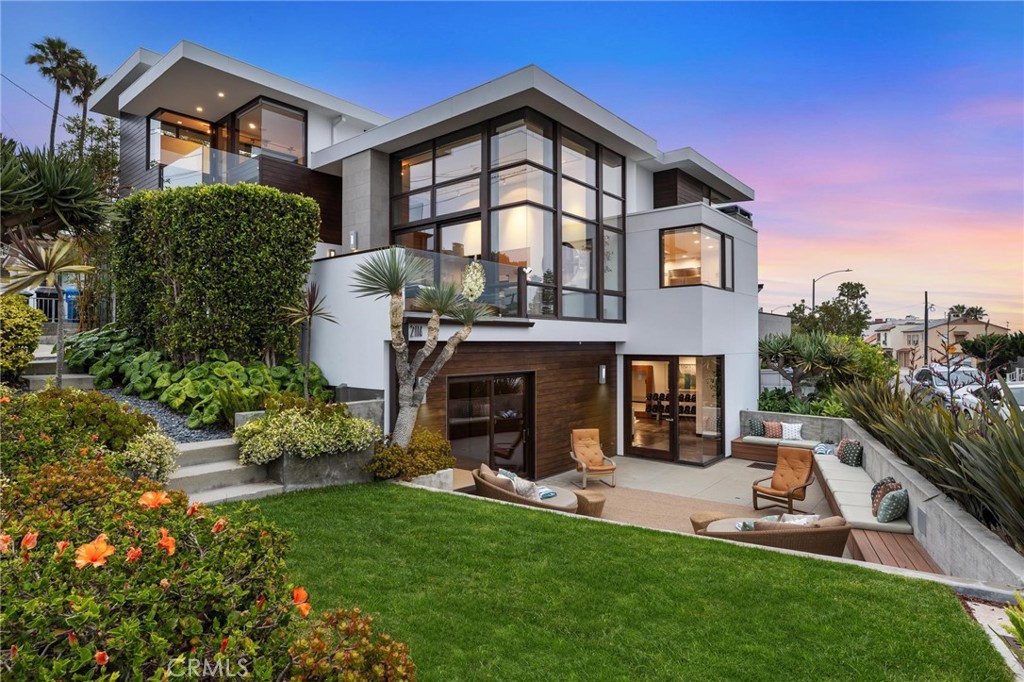 Welcome to “The Koa Lanai House,” a custom-designed architectural masterpiece by the late Patrick Killen, AIA—founder of Studio 9one2 and a pioneer of modernist beach design in Los Angeles. Set on a rare 3,524 sq ft corner lot just moments from the sand, this striking residence offers panoramic views from Malibu to Palos Verdes, including both Manhattan and Hermosa Beach piers—alongside exceptional indoor-outdoor living rarely found this close to the beach. Inside, the open-concept living space features approx 14-ft soaring ceilings, walls of glass, and newly refinished Brazilian cherry wood floors—each plank a unique work of art. A large terrace expands the living space, while the chef’s kitchen centers around a 9.5-ft custom Acacia Koa wood island with built-in pop-up TV, Sub-Zero fridge, Viking 6-burner range, wine fridge, walk-in pantry, and breakfast bar seating for six. A second terrace off the dining area offers views of Catalina and Palos Verdes. The main level also includes a powder room, recessed lighting, and integrated in-ceiling speakers. Upstairs, all three bedrooms feature ensuite baths, ocean views, and smart audio integration. The primary suite includes a custom-built-in platform bed, daybed nook, private ocean-view terrace, dual vanity bath with rainfall shower, ceiling-fill Acacia Koa soaking tub, and walk-in closet. The lower level houses an expansive flex space currently configured as a combined screening room and fitness area, with polished concrete floors, a 135" projection screen, wet bar, and decorative fireplace—plus a guest suite with full bath access and sliding doors to the patio. Additional highlights include a wine cellar, laundry room, and a rare Sand Section yard with wraparound seating, grass lawn, water feature, and sunset-view pebble patio. The home includes a recently replaced roof, A/C, dual tankless water heaters, Nuvo filtration system, Tesla charger, and a 3-car garage with deep-bay storage and built-in shelving. Tech upgrades include Savant smart controls and rooftop deck potential (buyer to verify feasibility). Ideally located near both piers, the Strand, top-rated Mira Costa High, and local favorites like Martha’s and The Bottle Inn—2114 Manhattan Avenue “The Koa Lanai House" is a modern coastal sanctuary with iconic views and timeless appeal.