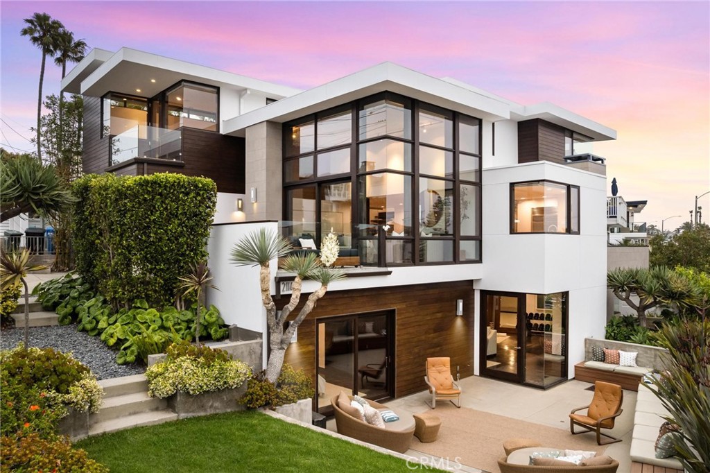 Welcome to “The Koa Lanai House,” a custom-designed architectural masterpiece by the late Patrick Killen, AIA—founder of Studio 9one2 and a pioneer of modernist beach design in Los Angeles. Set on a rare 3,524 sq ft corner lot just moments from the sand, this striking residence offers panoramic views from Malibu to Palos Verdes, including both Manhattan and Hermosa Beach piers—alongside exceptional indoor-outdoor living rarely found this close to the beach. Inside, the open-concept living space features approx 14-ft soaring ceilings, walls of glass, and newly refinished Brazilian cherry wood floors—each plank a unique work of art. A large terrace expands the living space, while the chef’s kitchen centers around a 9.5-ft custom Acacia Koa wood island with built-in pop-up TV, Sub-Zero fridge, Viking 6-burner range, wine fridge, walk-in pantry, and breakfast bar seating for six. A second terrace off the dining area offers views of Catalina and Palos Verdes. The main level also includes a powder room, recessed lighting, and integrated in-ceiling speakers. Upstairs, all three bedrooms feature ensuite baths, ocean views, and smart audio integration. The primary suite includes a custom-built-in platform bed, daybed nook, private ocean-view terrace, dual vanity bath with rainfall shower, ceiling-fill Acacia Koa soaking tub, and walk-in closet. The lower level houses an expansive flex space currently configured as a combined screening room and fitness area, with polished concrete floors, a 135" projection screen, wet bar, and decorative fireplace—plus a guest suite with full bath access and sliding doors to the patio. Additional highlights include a wine cellar, laundry room, and a rare Sand Section yard with wraparound seating, grass lawn, water feature, and sunset-view pebble patio. The home includes a recently replaced roof, A/C, dual tankless water heaters, Nuvo filtration system, Tesla charger, and a 3-car garage with deep-bay storage and built-in shelving. Tech upgrades include Savant smart controls and rooftop deck potential (buyer to verify feasibility). Ideally located near both piers, the Strand, top-rated Mira Costa High, and local favorites like Martha’s and The Bottle Inn—2114 Manhattan Avenue “The Koa Lanai House" is a modern coastal sanctuary with iconic views and timeless appeal.