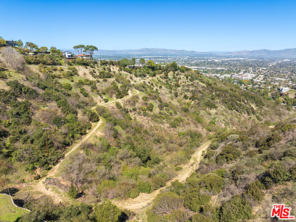 Set just below iconic Mulholland Drive, this nearly 1.5 acre parcel offers a rare opportunity to build in one of Los Angeles' most exclusive and storied settings. Once part of a larger celebrity-owned estate, the land is now offered as a standalone development site and brimming with potential. Surrounded by natural beauty and perched above a dramatic canyon backdrop, the setting offers exceptional privacy, expansive proportions, and inspiring views that stretch into the valley below. Located in the coveted 90210 zip code (Beverly Hills Post Office), with easy access to both the Westside and the Valley, this parcel is a blank canvas for a visionary builder or end-user looking to create something extraordinary. Vacant land of this caliber and scale is nearly impossible to find in today's market. A rare chance to shape the next legacy property in a world-class location.