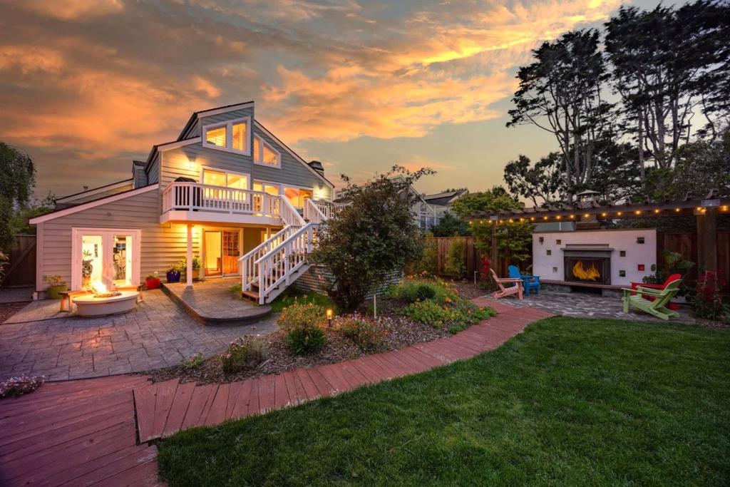 Welcome to coastal living in the sought-after Alsace Lorraine neighborhood. This industrial/boutique-style home greets with lush landscaping, bluestone pavers, and a private front porch. Inside, the spacious great room features exposed pine beam ceilings, built-in bookcases, and welcoming fireplace, perfect for cozy gatherings. Two full-size bedrooms and a full bath complete the first floor. Upstairs, a soaring pine-clad living room with second fireplace flows into the modern chef's kitchen, where high-end appliances, stainless-steel countertops, and custom cabinetry set the stage for effortless entertaining. Choose from banquet seating, bar stools at the peninsula, or dine al fresco on the spacious deck. The primary suite impresses with antique barn doors, a chandelier-lit bath, and extensive custom closets. The 3rd floor loft offers a sunlit gallery and a newly permitted 4th bedroom with an ocean view. Step onto the deck overlooking a private backyard retreat with an outdoor fireplace, greenhouse, and fruit trees, including lemon, pear, apple, and mandarin. An artist studio/workshop sits off the attached two-car garage. Owned solar. Just a short walk to the beach and Main Street, with easy access to Hwy 1 & 92. A rare find in one of Half Moon Bay's most desirable communities!