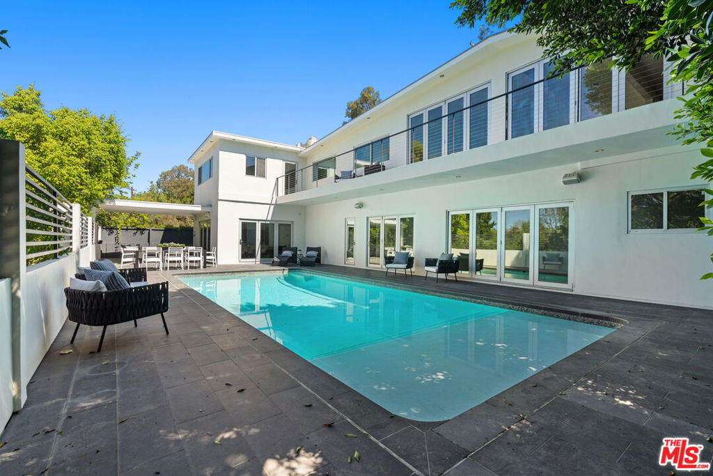 Nestled in the iconic Hollywood Hills on Woodrow Wilson Drive's "celebrity row", this stunning mid-century home with pool offers a harmonious balance of indoor and outdoor quintessential Southern California living. Spanning over 3,400 square feet, the residence includes 4 spacious bedrooms and 4.5 bathrooms with an expansive open layout and oak floors throughout. The main level features a sleek modern living space including a Chef's gourmet kitchen fitted with Modulo Cucine cabinets, Thermador appliances and island with breakfast bar that is perfect for entertaining. Adjoining dining and living areas are framed by large folding glass doors opening to a newly constructed second level patio showcasing the serene surroundings and sweeping treetop vistas. The lower level is a private haven, featuring a luxurious primary suite with a spa-like bathroom, walk-in closet, and direct access to the patio and heated in-ground pool. Additional rooms include an office and ensuite bedroom, providing ample space for work, guests, or family. Private outdoor area is designed for relaxation and entertaining, with the potential to add an outdoor kitchen for alfresco dining. This thoughtfully designed home is equipped with integrated speakers, a security system, and an electric vehicle charging station in the attached two-car garage. Situated in one of the most sought-after neighborhoods in the Hollywood Hills offering unparalleled privacy while remaining conveniently close to hiking trails, world-class dining, shopping, and entertainment including Universal Studios, The Hollywood Bowl, and the Hollywood Walk of Fame. Also offered for sale at $2,650,000