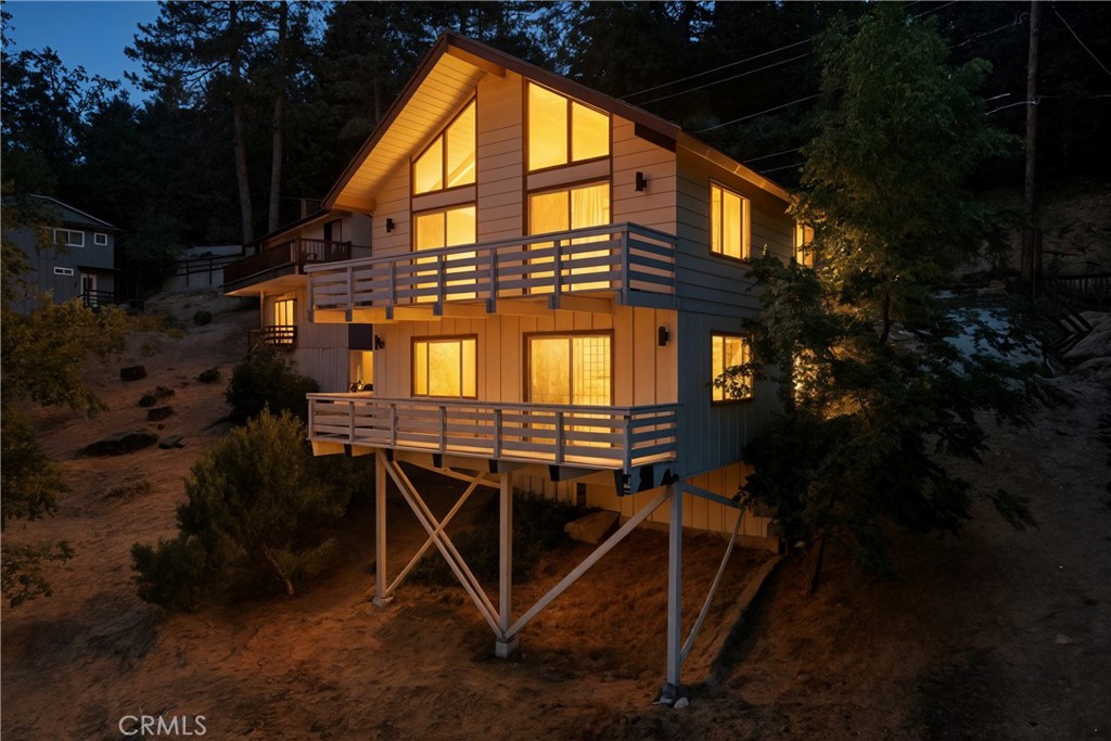Escape to this beautifully rehabbed cabin, perfectly tucked away in the trees. With a gentle slope to level entry and a desirable south facing orientation, this open floor plan showcases exposed beam ceilings and expansive picture windows that fill the space with natural light and frame peaceful pine views. The home features a main level that flows seamlessly with a spacious kitchen, dining area, and cozy living room anchored by a wood burning fireplace. Upstairs, a loft provides extra sleeping space, with a closet. While the lower level features a private primary suite with a full size bath and a family room for relaxing or entertaining. Step outside to two inviting decks that are perfect for morning coffee or evening sunsets. A hidden hatch leads to the laundry area beneath the home, keeping chores discreet and out of the way. Pride of ownership is evident throughout. With fruit trees on the property and Just minutes from Lake Gregory, this home offers the perfect blend of comfort, privacy, and convenience, whether you are planning weekend getaways or full time mountain living.