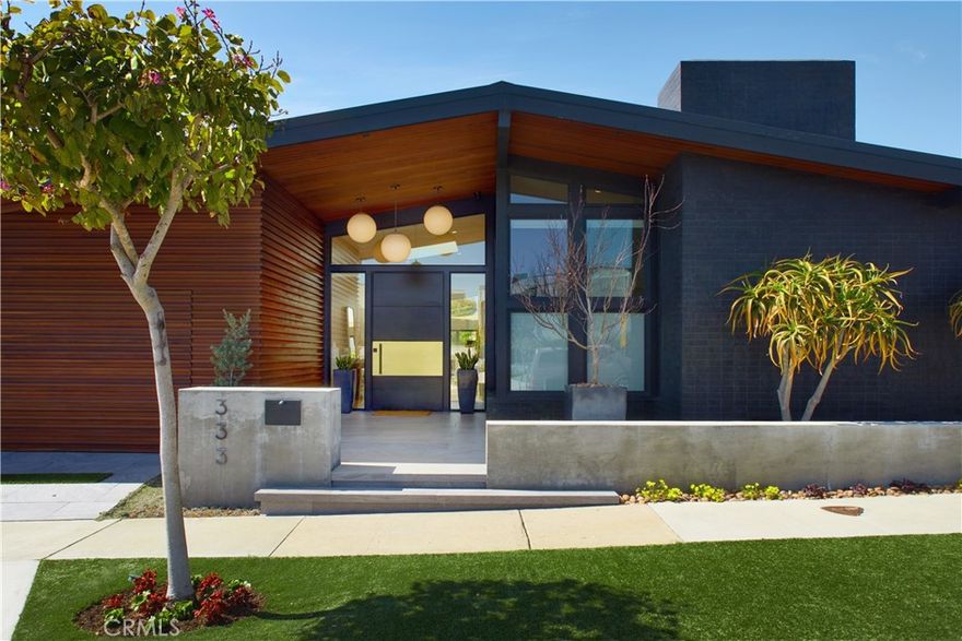Located within the prestigious Cameo Shores enclave and featuring scenic creek and peek-a-boo ocean views, this magnificent Mid-Century Modern home maintains its original character while incorporating today’s preferred design aesthetic. Reflecting an extensive 2020 remodel designed by Lindye Galloway with Principle Design & Construction as contractor, the home is warm, inviting and an ideal match for a wide variety of lifestyles. A custom glass-framed door provides passage to the extra-open and light-filled interior, which spans approximately 3,647 square feet on one impressive level. Four en suite bedrooms and four- and one-half baths offer their own unique style while providing comfort and privacy from main living areas. Vaulted open-beam ceilings, clerestory windows, and several sets of fold-away glass doors combine to infuse the home with an indoor/outdoor flow. Main public spaces include a living room warmed by a fireplace with floor-to-ceiling surround and a floating stone hearth, while the dining room opens to the outdoors. Anchored by two islands, one for prep and another for casual dining, the stunning kitchen shines with porcelain-slab countertops, waterfall edges, custom tile backsplash, custom contemporary cabinetry, a pass-thru to the patio for easy serving, a butler’s pantry, and top-tier appliances from Sub-Zero, Wolf and Miele. On-trend design continues in the exclusive primary suite, where a book-matched stone fireplace wall, high ceiling, floor-to-ceiling windows, and a private bath with marble countertop, oversized shower and freestanding tub are on display. The casually upscale home also features wood and tile flooring, new Milgard windows and doors, designer accent tile throughout, quartz counters in secondary baths, and an attached three-car garage. High-tech systems include owned solar power, Nest thermostats, Luma security cameras, and Savant Home Automation. Terraced grounds extend almost .34 acres and reveal a pool and spa with waterfall and automatic cover, lifelike turf, and a dining patio for outstanding outdoor entertaining.
