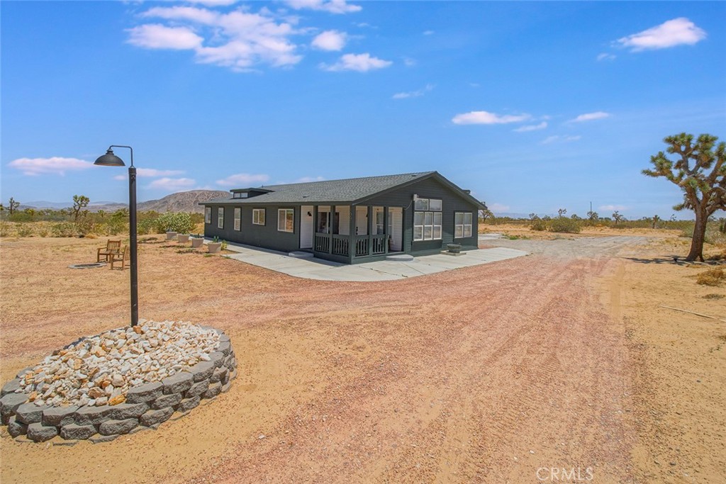 2 HOMES ON 5 ACRES – INCOME POTENTIAL + INCREDIBLE VIEWS! Here’s your rare chance to own a versatile 5-acre desert retreat in Landers, with two separate homes and stunning panoramic views of the surrounding Mojave landscape. Whether you're looking to live in one and short-term rent the other this unique setup delivers comfort, flexibility, and opportunity under the wide-open desert skies. The main residence is a spacious triple-wide 3-bedroom, 2-bath manufactured home on a permanent foundation, offering over 2,000 square feet of thoughtfully designed living space. Abundant clerestory windows and plantation shutters fill the home with natural light, while thoughtful updates like laminate flooring, a stacked-stone gas fireplace, and a combination of central A/C and wall-mounted evaporative cooling ensure year-round comfort. The primary suite includes an extended sitting/reading room and a luxurious bathroom with dual sinks, a separate soaking tub, and standalone shower—perfect for relaxing after a long desert day. The detached 3-car garage, nearly 1,000 square feet, includes its own bathroom and two storage rooms, ideal for workshop space or future conversion. Between the garage bays, a motorized-door breezeway creates a breezy lounge or game area with uninterrupted views of Goat Mountain—a perfect setting for sunsets, gatherings, or peaceful solitude. Tucked to the side of the main home, a thoughtfully renovated 1-bedroom, 1-bath homestead cabin (approx. 620 square feet) complete with modern updates and rustic charm. This property is ideally located to experience everything Landers has to offer: Integratron, Gubler Orchids, Joshua Tree Bee Co, Giant Rock, and King of the Hammers, just to name a few. You're also just a short drive to the boulders of Joshua Tree, Pioneertown, Pappy & Harriet’s, and Palm Springs. Whether you're seeking a primary residence, income property, desert escape, or investment with room to grow, this Landers gem checks all the boxes. Don’t wait—this 2-on-a-lot opportunity with endless potential won't last long!